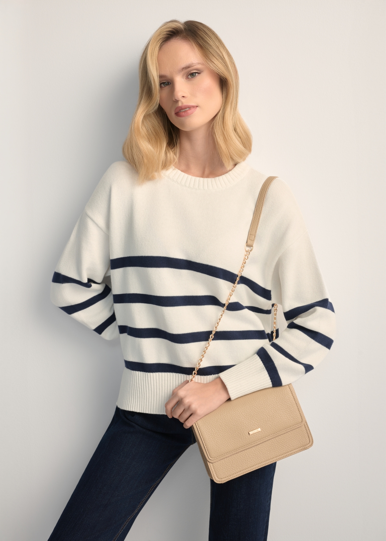 Small beige women's handbag TOREC-1015-1B(W26), front view of the product on a model, half of the silhouette visible.