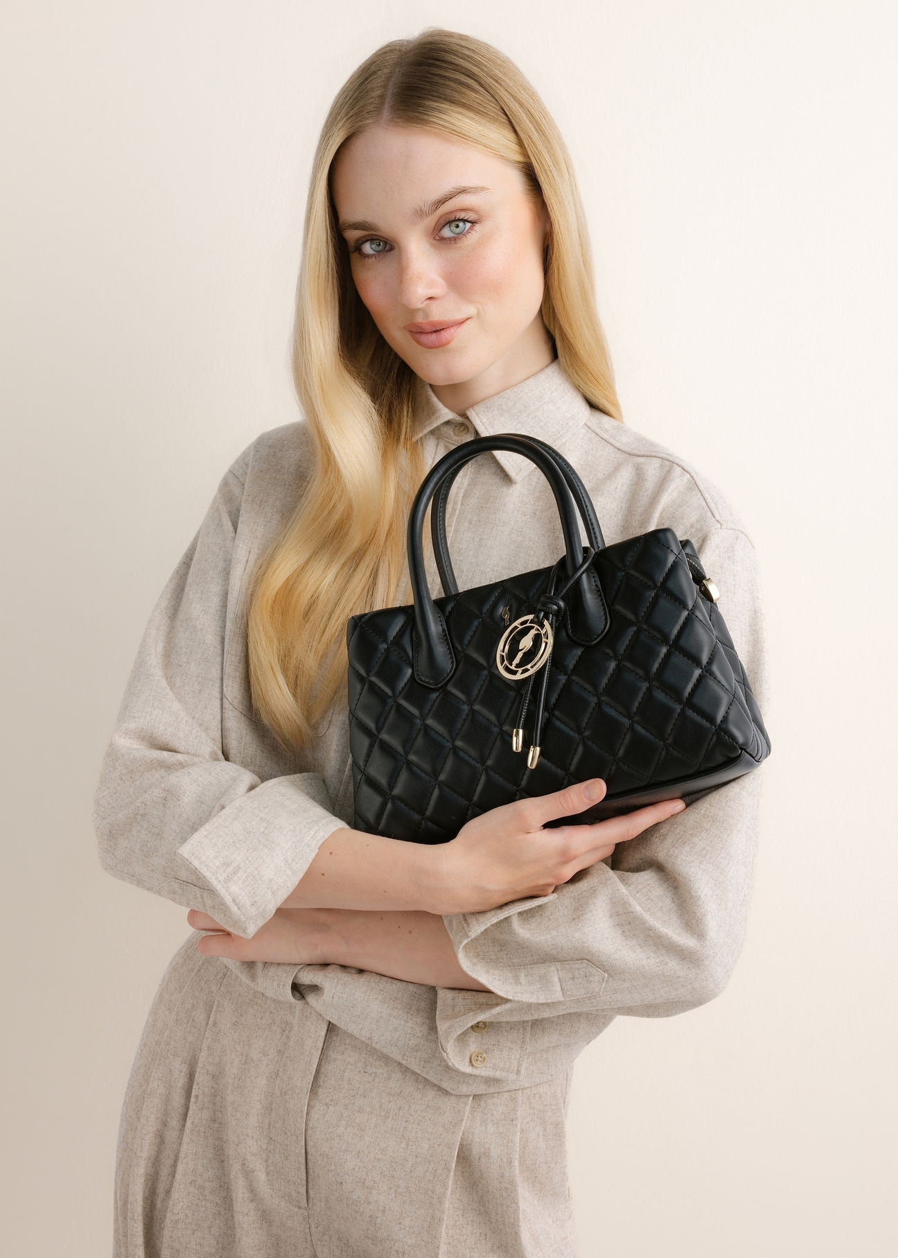 Quilted black women's handbag TOREC-1312-99(Z26), front view of the product on a model. Half-body shot.
