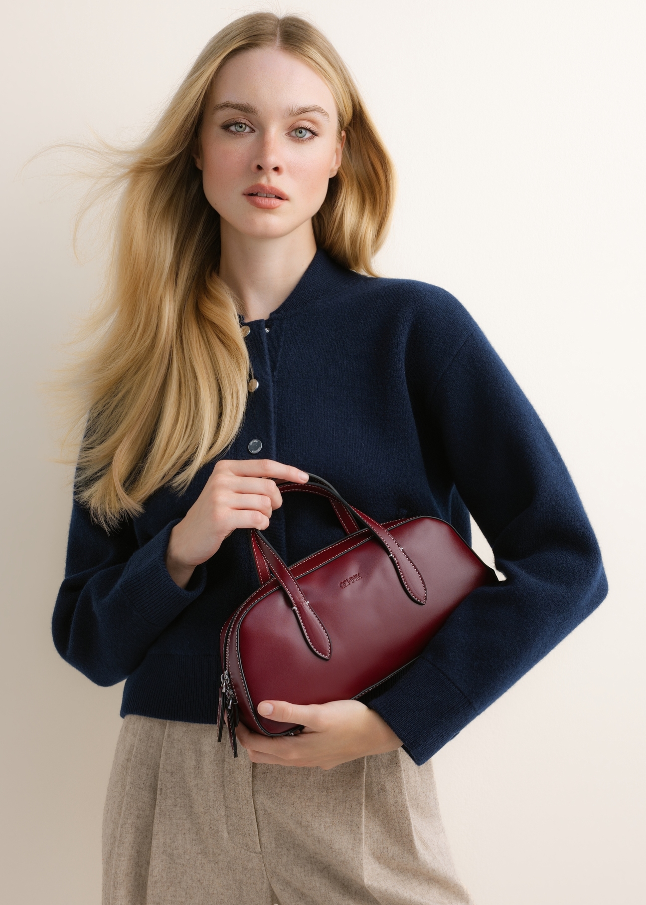 Small dark red women's handbag TOREC-1382-4C(Z26); front view of the product held in a model's hands against a light background.
