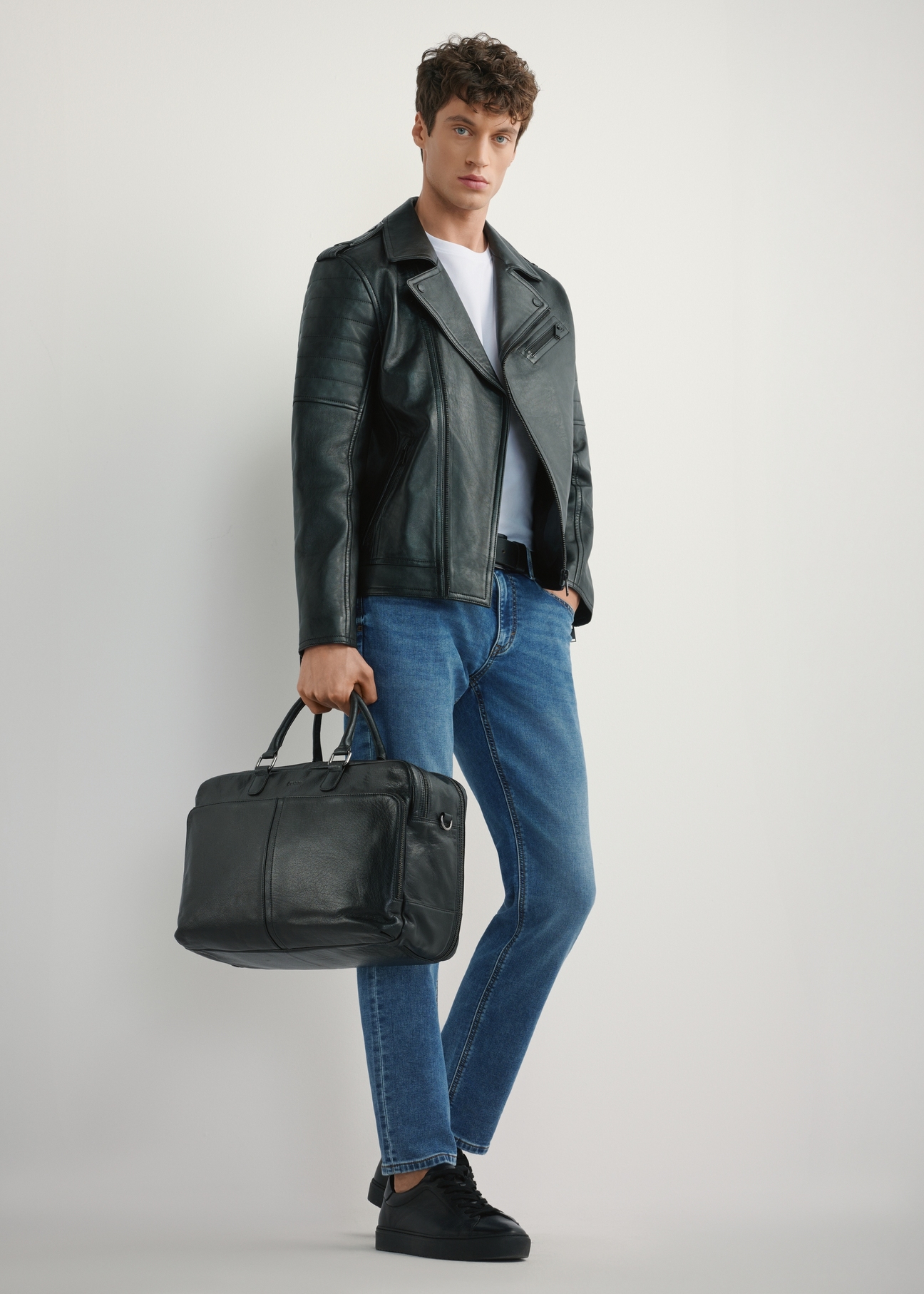 Large black leather men's bag TORMS-0489-99(W26) - slightly diagonal view of the product, held by the model, against a light background. The entire silhouette is visible.