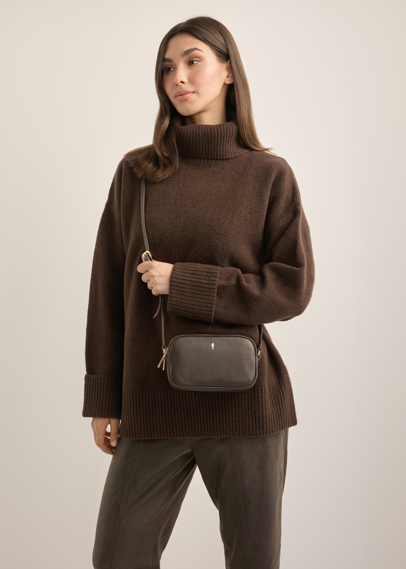 Small women's leather handbag in dark brown TORES-1152-1I(Z26), front view of the product on a model. Half of the silhouette visible.