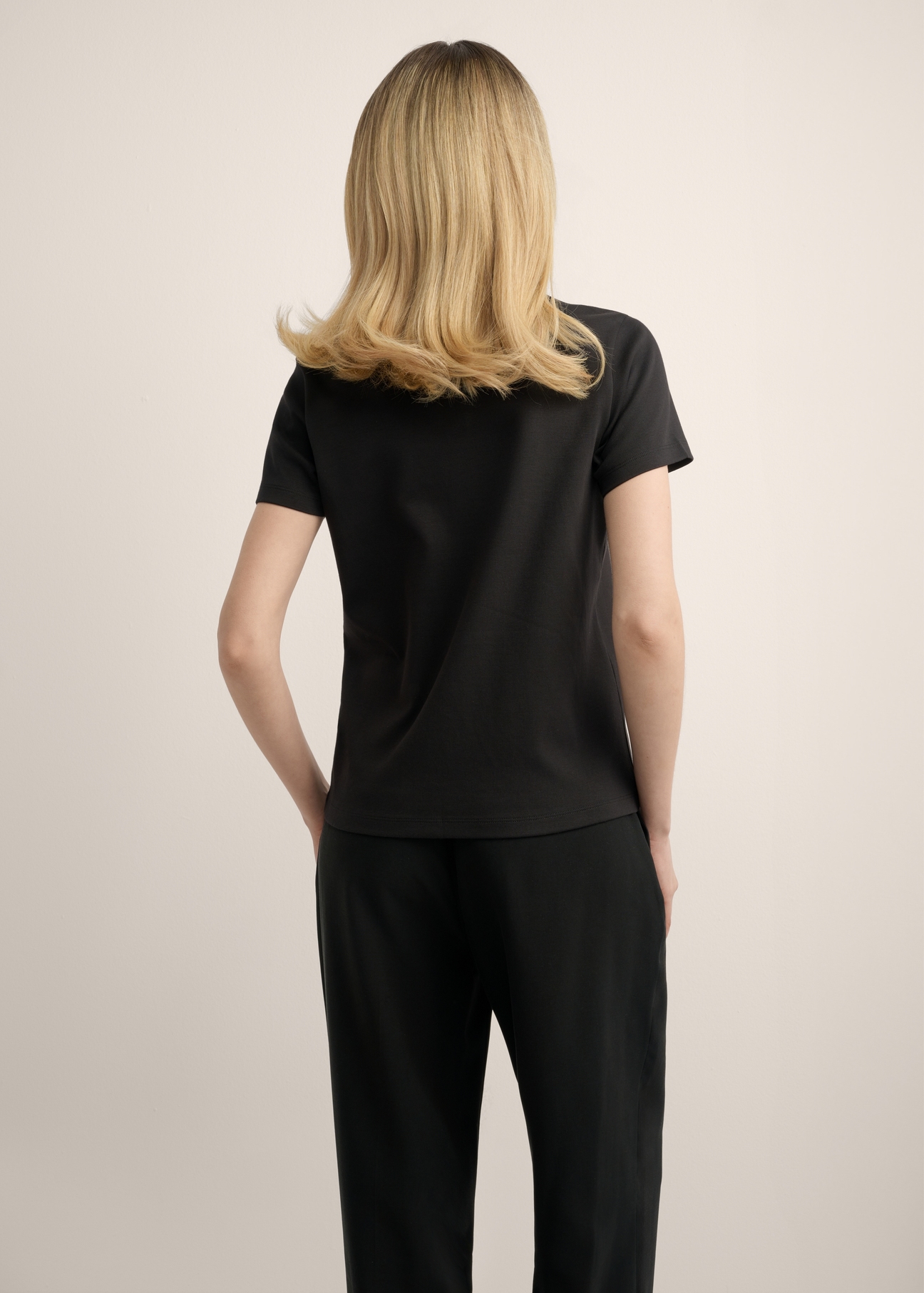 Women's black cotton t-shirt TSHDT-0144-99(Z25), back view of the product on the model. Half of the silhouette visible.