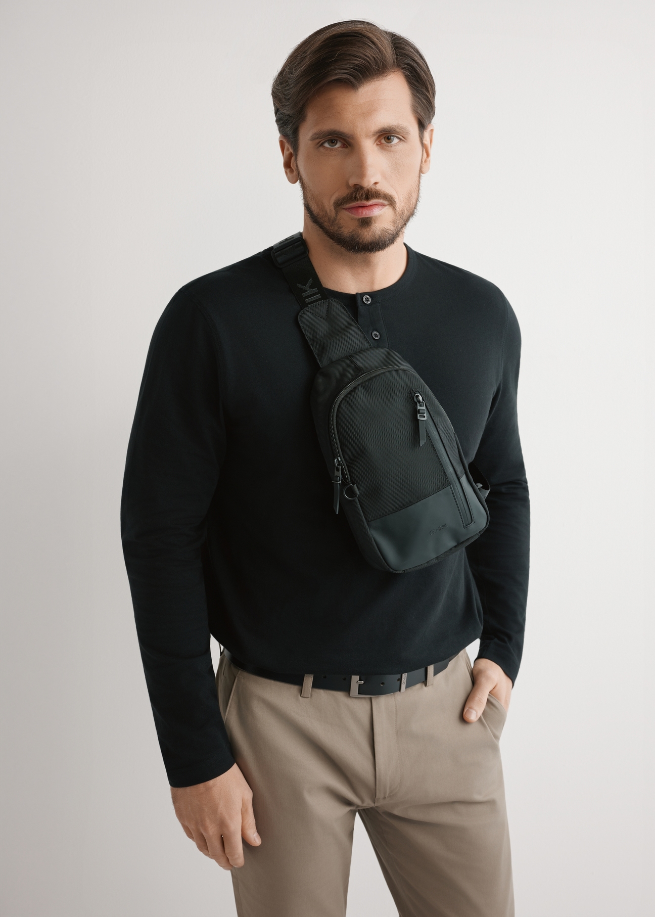 Black men's crossbody bag TORMN-0419-99(W26) - product view on model, against a light background. Knee-length silhouette visible.