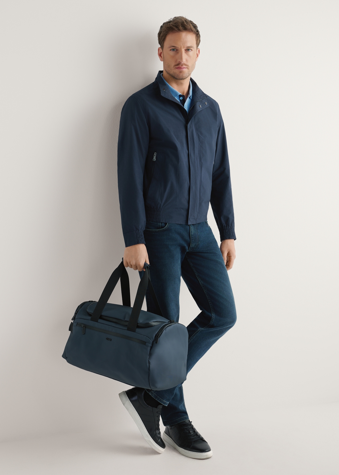 Navy blue TORMN-0412-7D(W26) travel bag - product view, held by the model, against a light background. Full body visible.