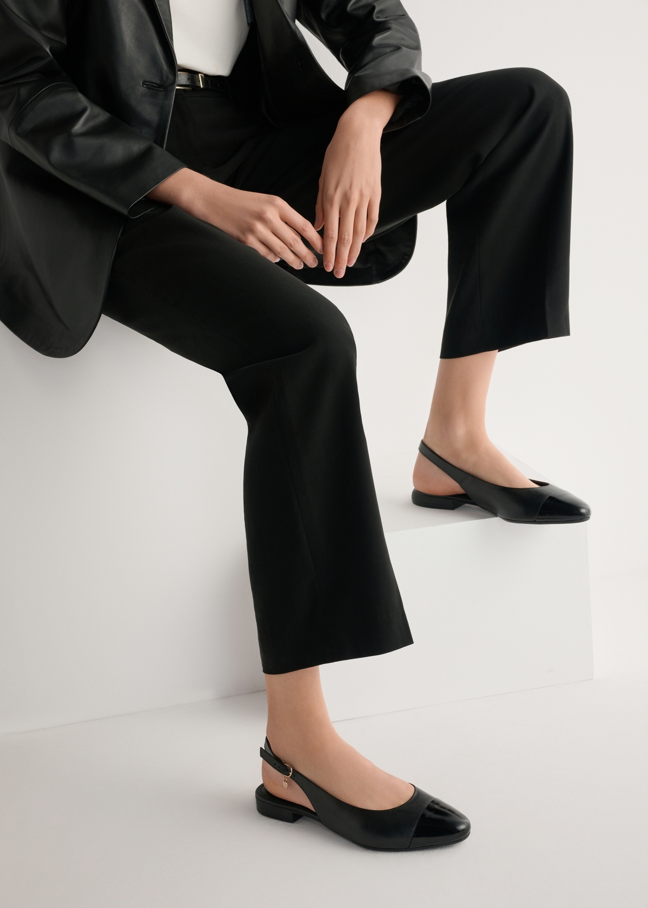 Black leather ballet flats without a heel BUTYD-1052A-99(W26), side view of the product on the model, half of the silhouette visible.