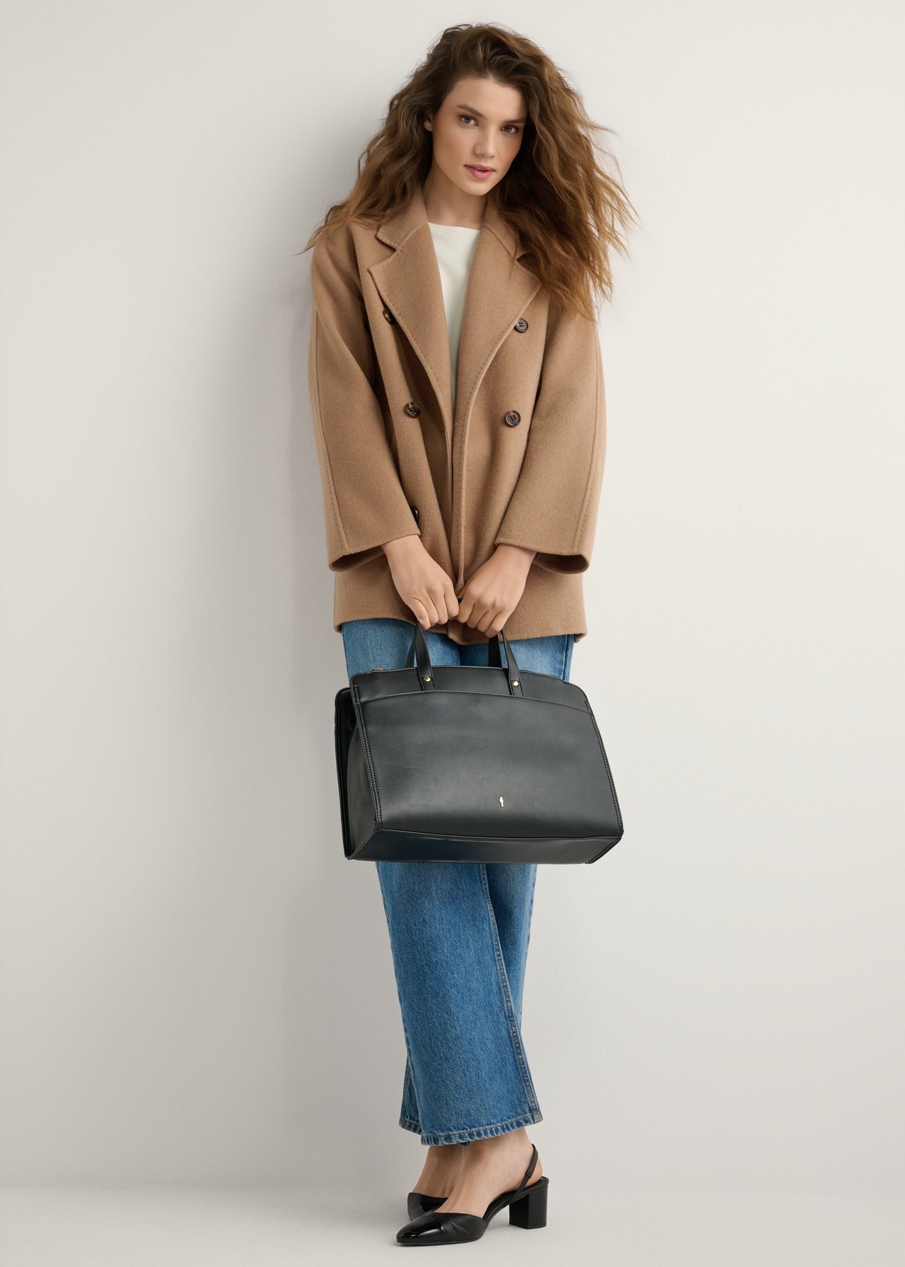 Black women's imitation leather bag TOREC-1143-99(W26), product view in model's hand. Full body visible.