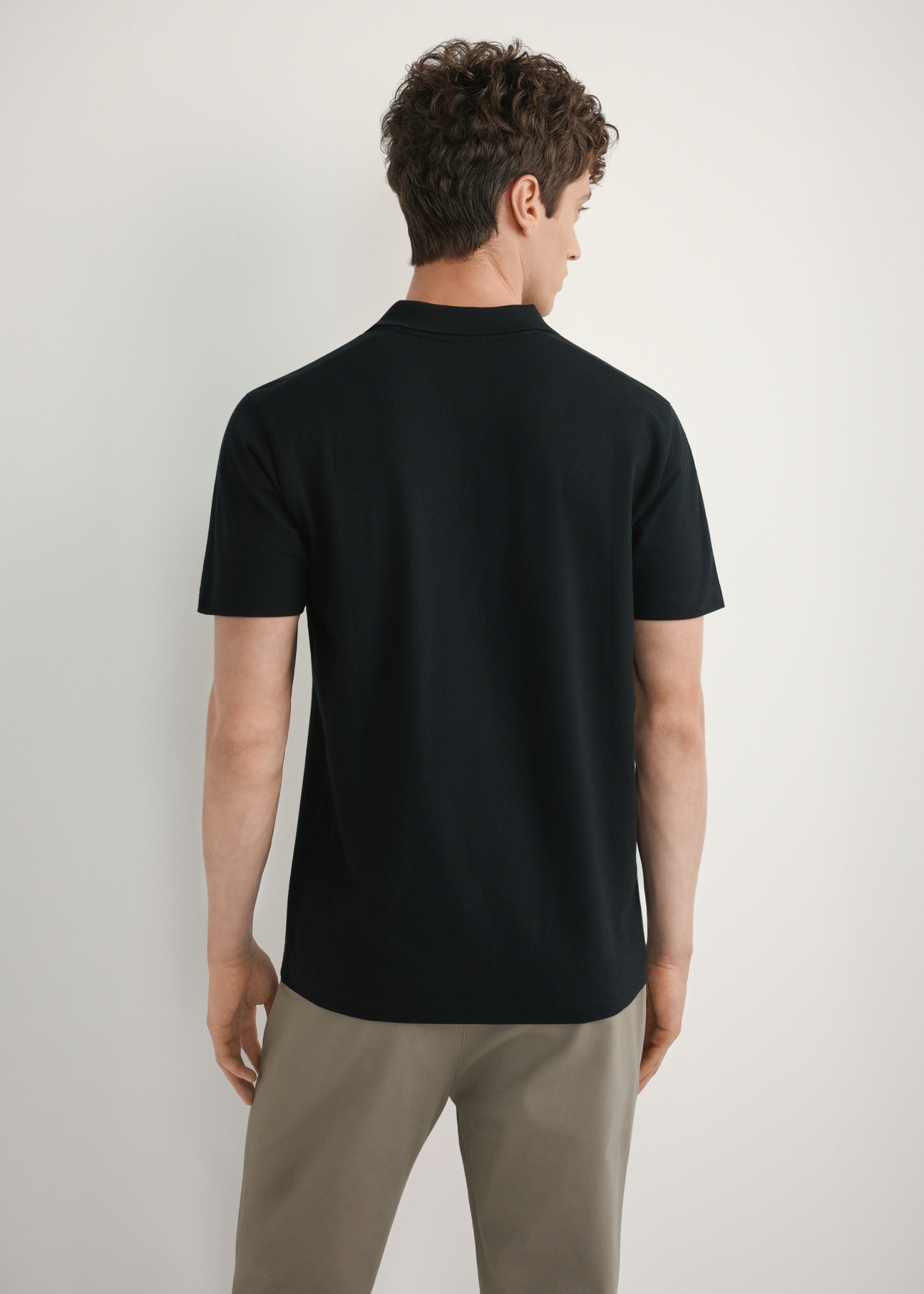 Men's black polo shirt POLMT-0084-99(W26) - back view of the product, on a model, against a light background. Half of the silhouette visible.