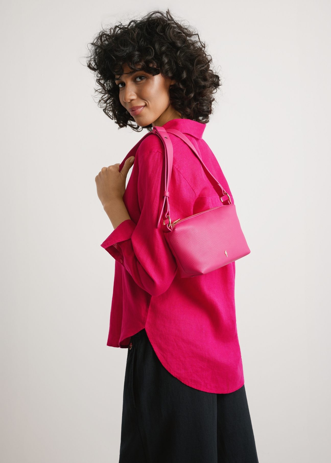 Small fuchsia women's handbag TOREC-0882-5E(W26) - front view of the product, on a model, against a light background. Half-length silhouette visible.