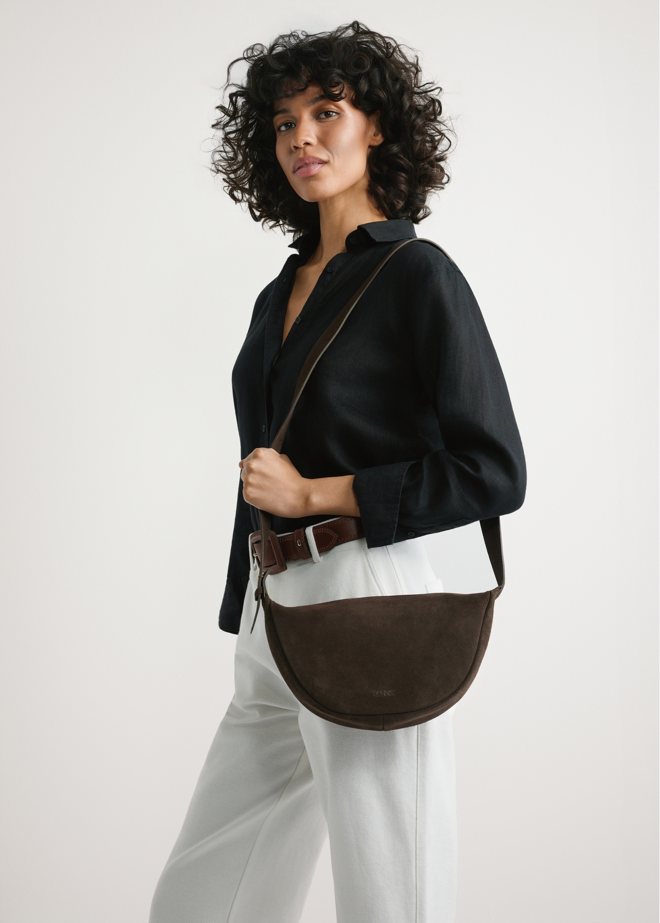 Dark brown leather semi-circular handbag TORES-1309-1I(W26), product view on model's shoulder. Half of silhouette visible.