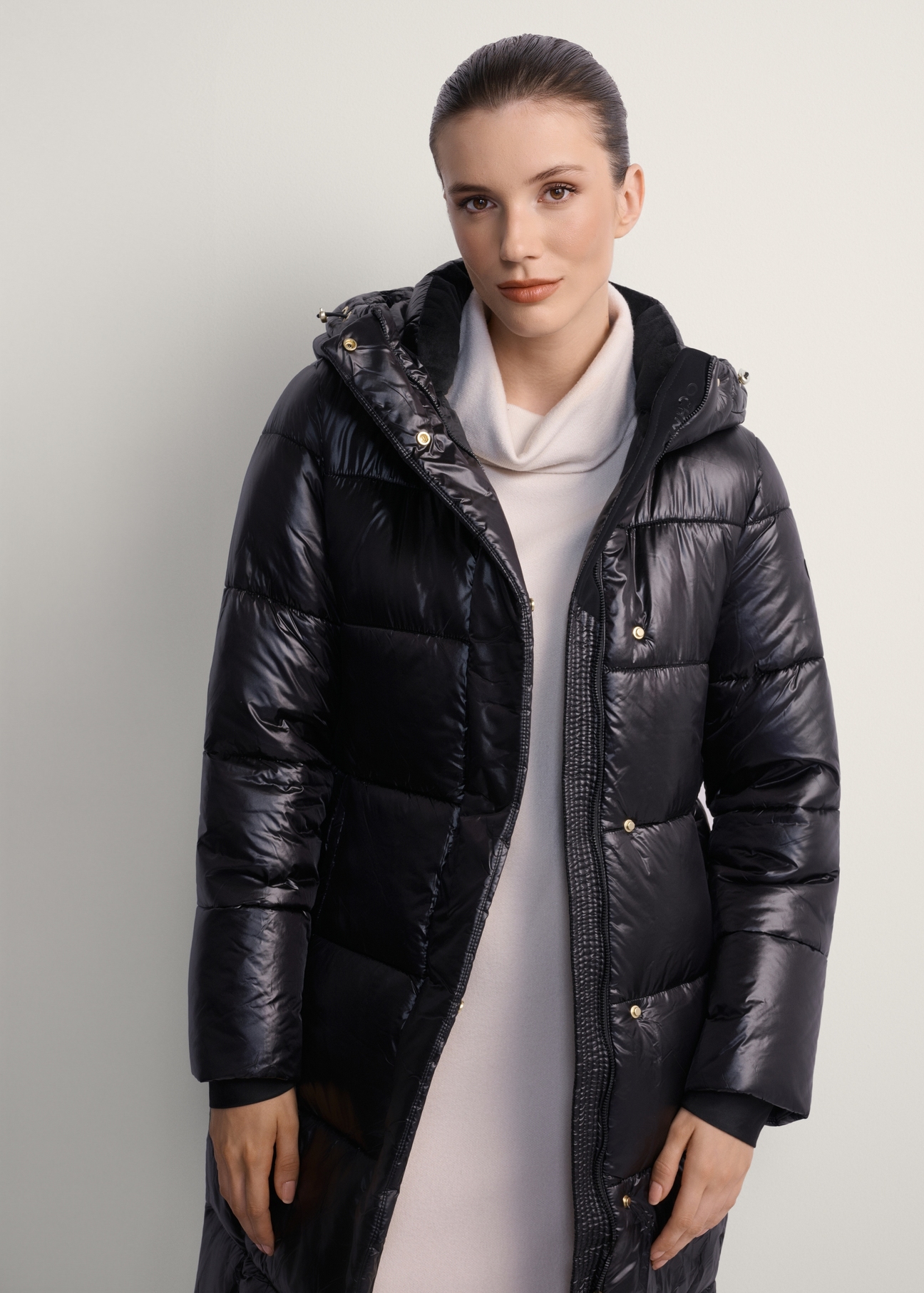 Black long women's winter jacket KURDT-0531A-99(Z25), product view from the front on the model, half of the silhouette visible.