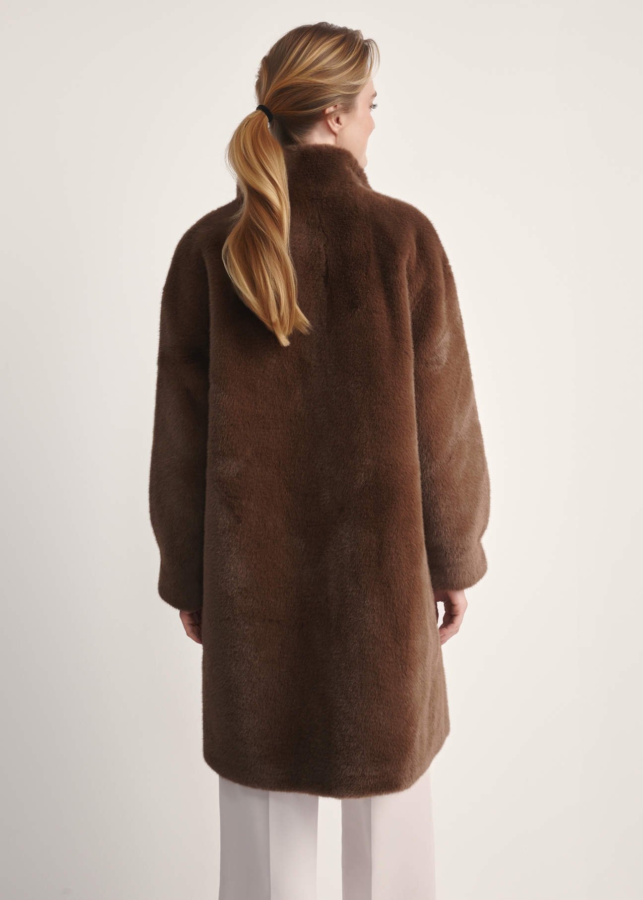 Elegant brown women's fur coat FUTDP-0050-89(Z25), product view from the back on the model, half of the silhouette visible.