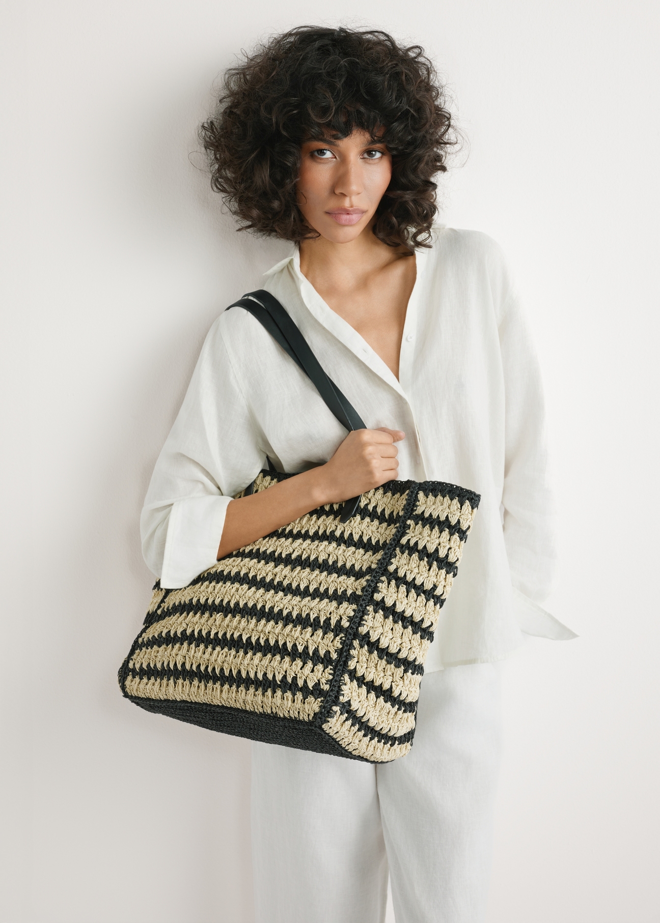 Women's natural straw handbag TOREC-1226-1E(W26) - product view slightly diagonal, on a model, against a light background. Half of the silhouette visible.