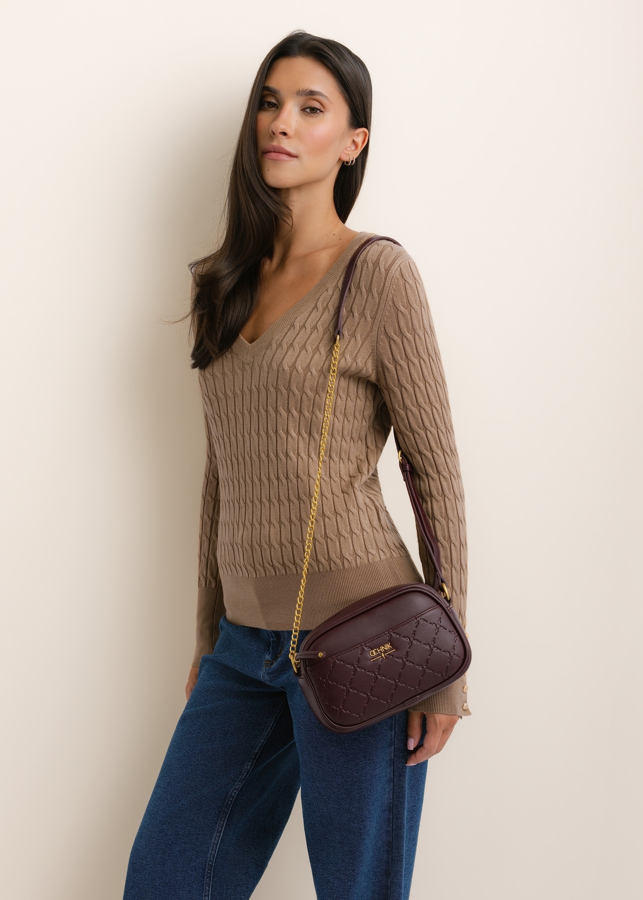 Burgundy small women's handbag TOREC-1285-4P(Z26), front view of the product, on a model, on a light background. Half of the silhouette visible.