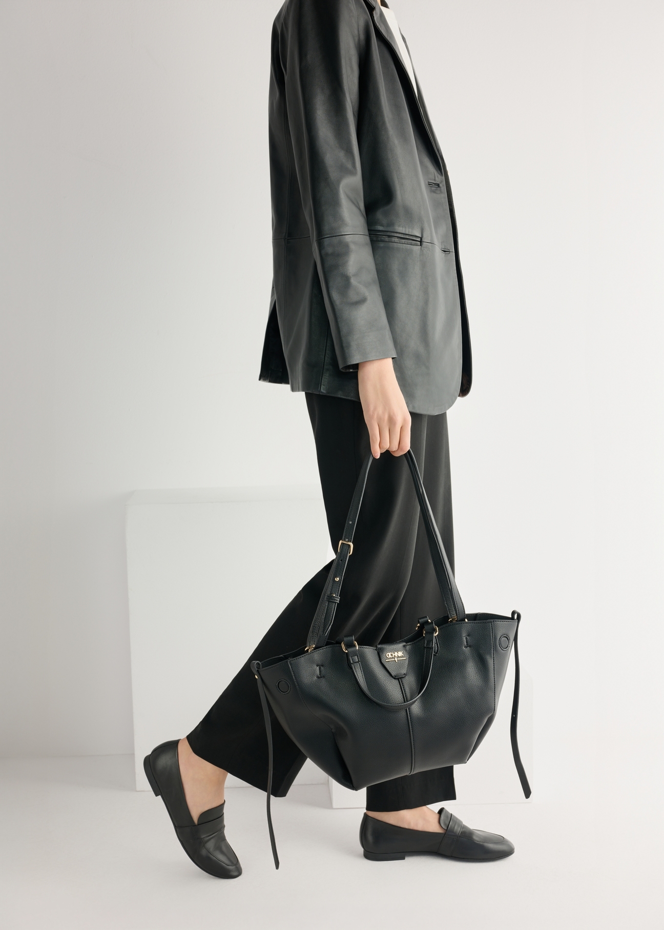 Women's black leather moccasins BUTYD-1074A-99(W26), product view from the front on the model, half of the silhouette visible.