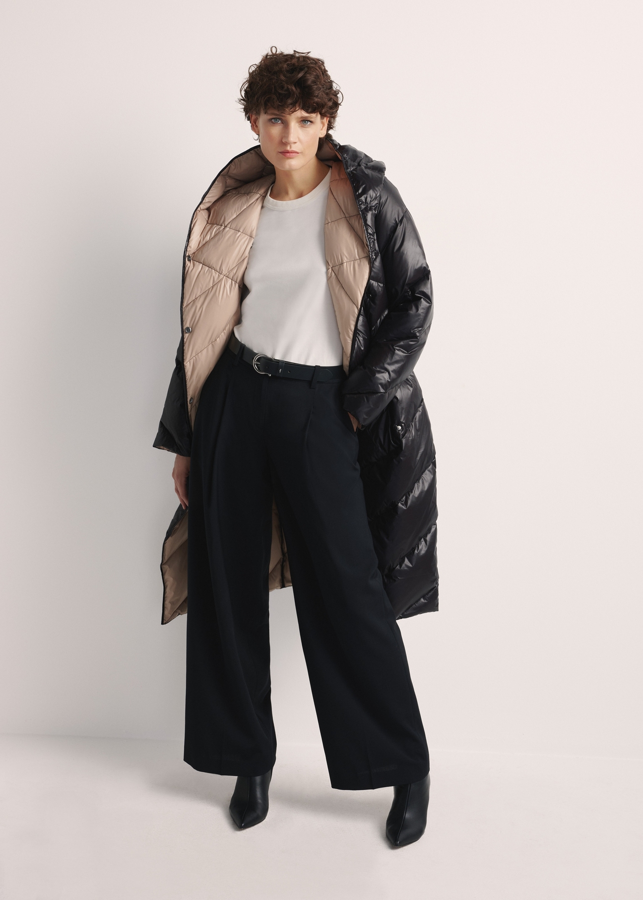 Long black women's winter jacket KURDT-0542A-98(Z25), product view from the front on the model, the whole silhouette is visible.