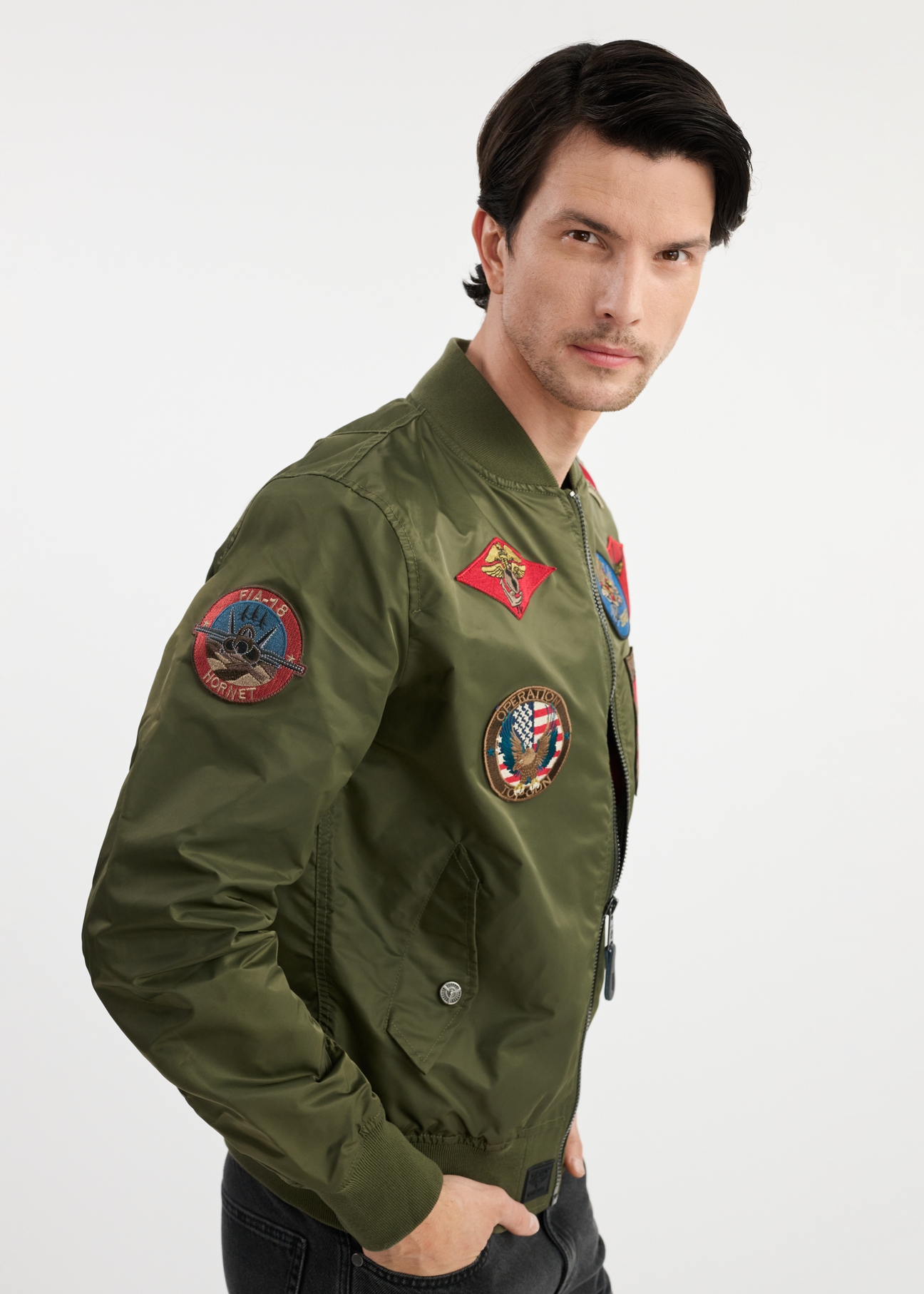 Olive men's TOP GUN KURMT-0381-57(W25) bomber jacket - side view on model on white background. Half of the silhouette visible.