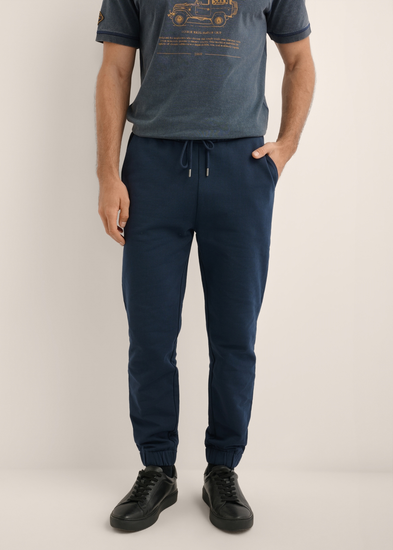 Men's navy blue sweatpants SPOMT-0128-7E(Z26), front view of the product on the model. Half of the silhouette visible.