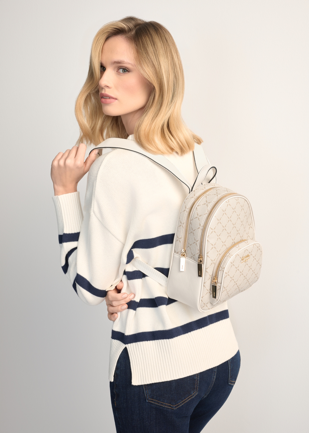 Cream women's backpack with monogram TOREC-1026-0P(W26), product view on model's shoulder. Half silhouette visible.