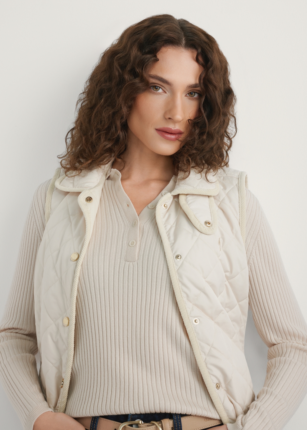 Light beige women's quilted vest KAMDT-0036-0B(W26) - front view of the product, on a model, against a light background. Half of the silhouette visible.