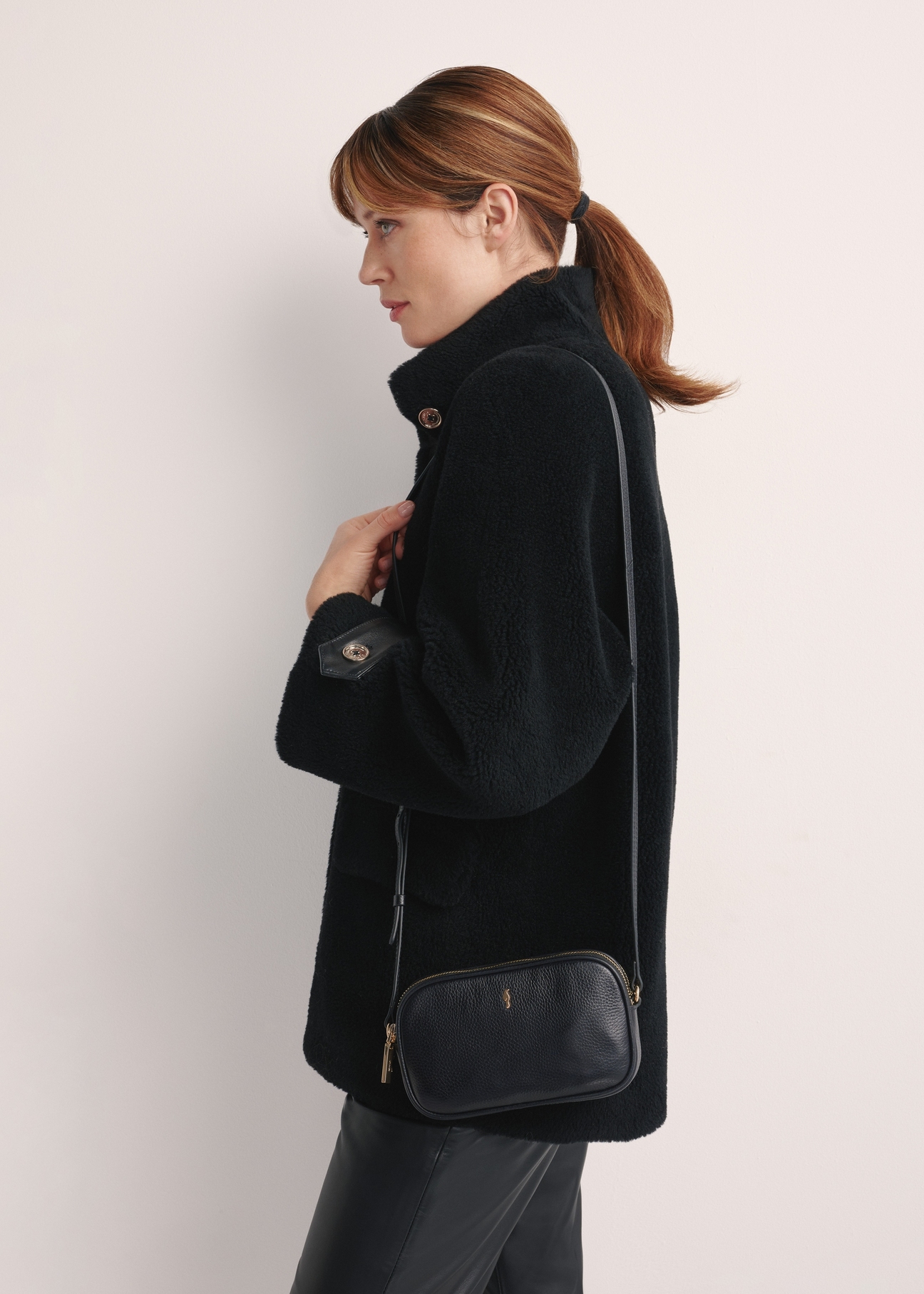 Small leather women's handbag in black TORES-1152-99(Z25), front view of the product on the model, half of the silhouette visible.