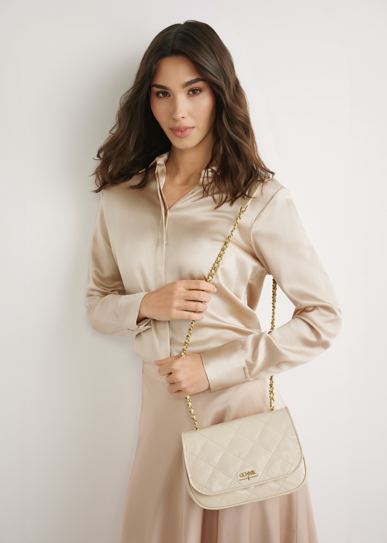 Cream patent leather women's handbag TORES-1297-0B(W26), front view of the product on a model. Knee-length silhouette visible.