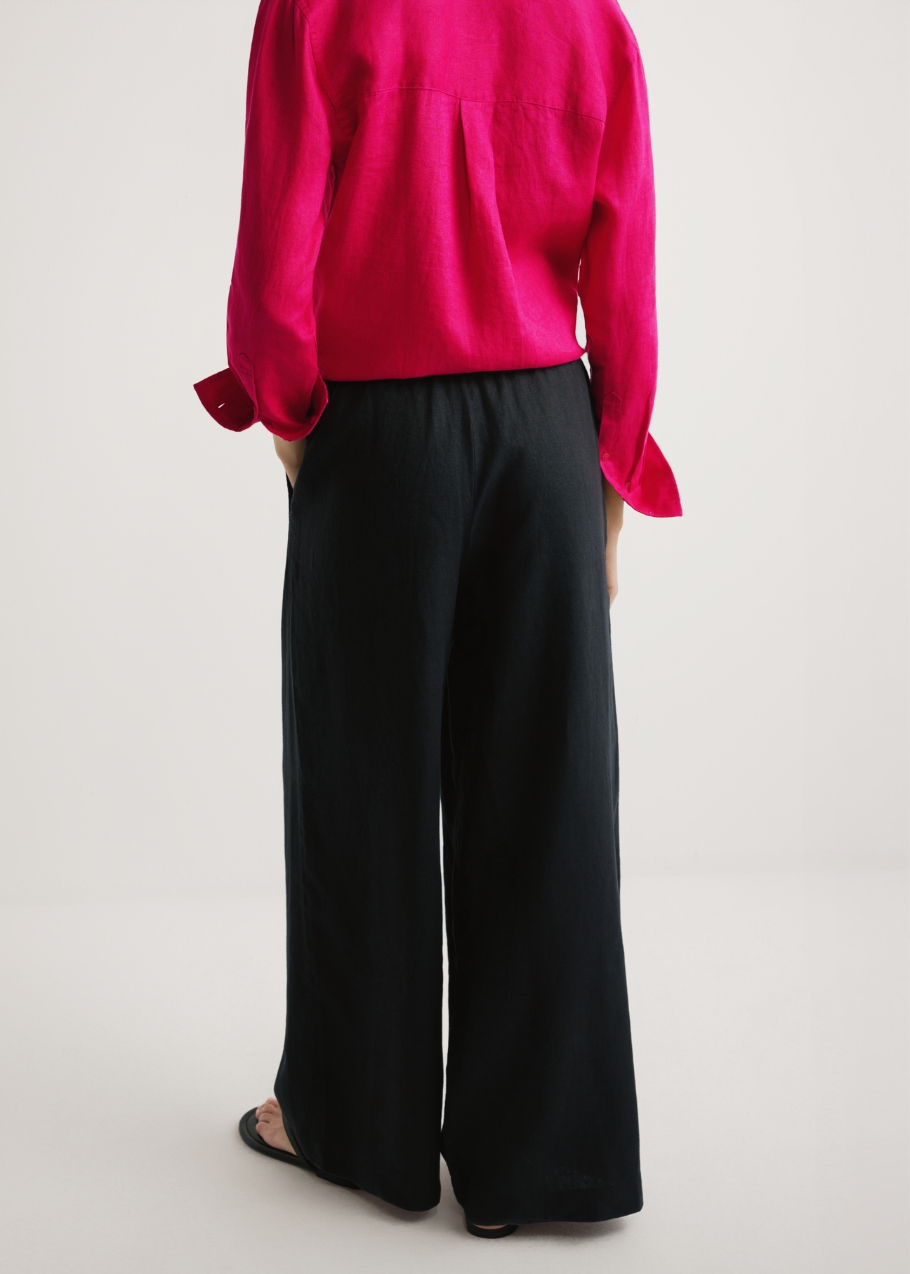 Women's black linen trousers SPODT-0124-99(W26) - back view of the product, on a model, against a light background. Half of the silhouette visible.