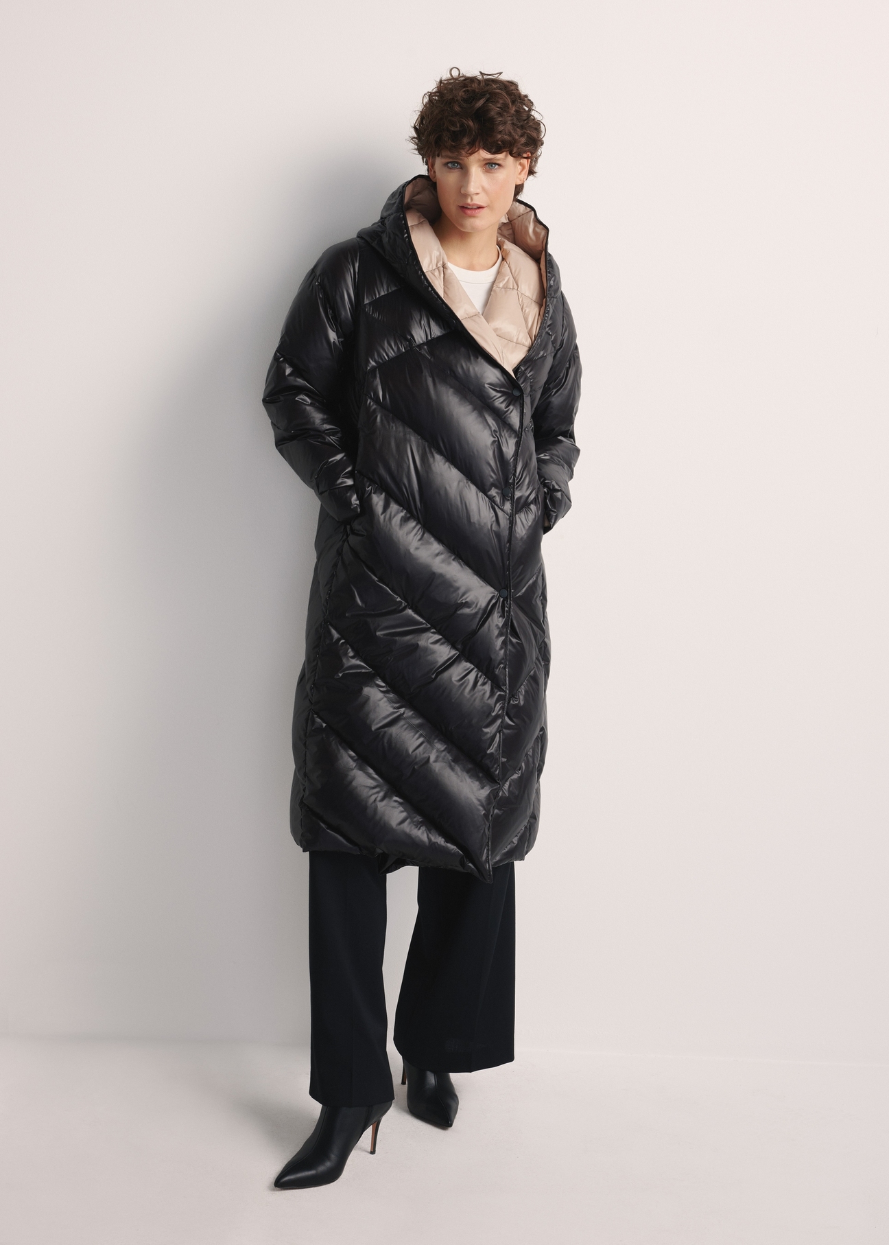 Long black women's winter jacket KURDT-0542A-98(Z25), product view from the front on the model, the whole silhouette is visible.
