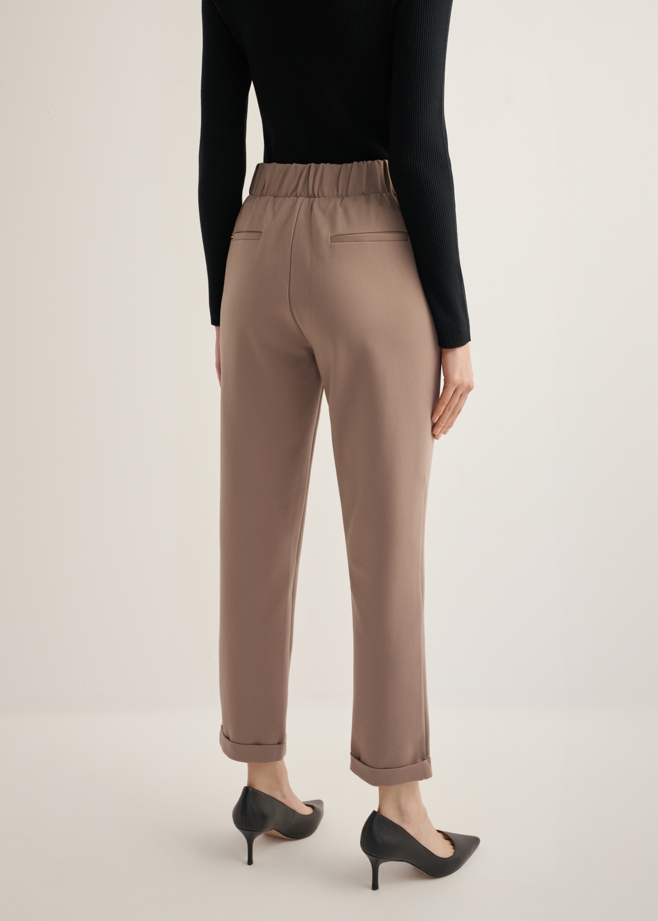Women's trousers with a crease in a cool beige color SPODT-0098-1K(Z26), view of the product from the back on the model, half of the silhouette visible.