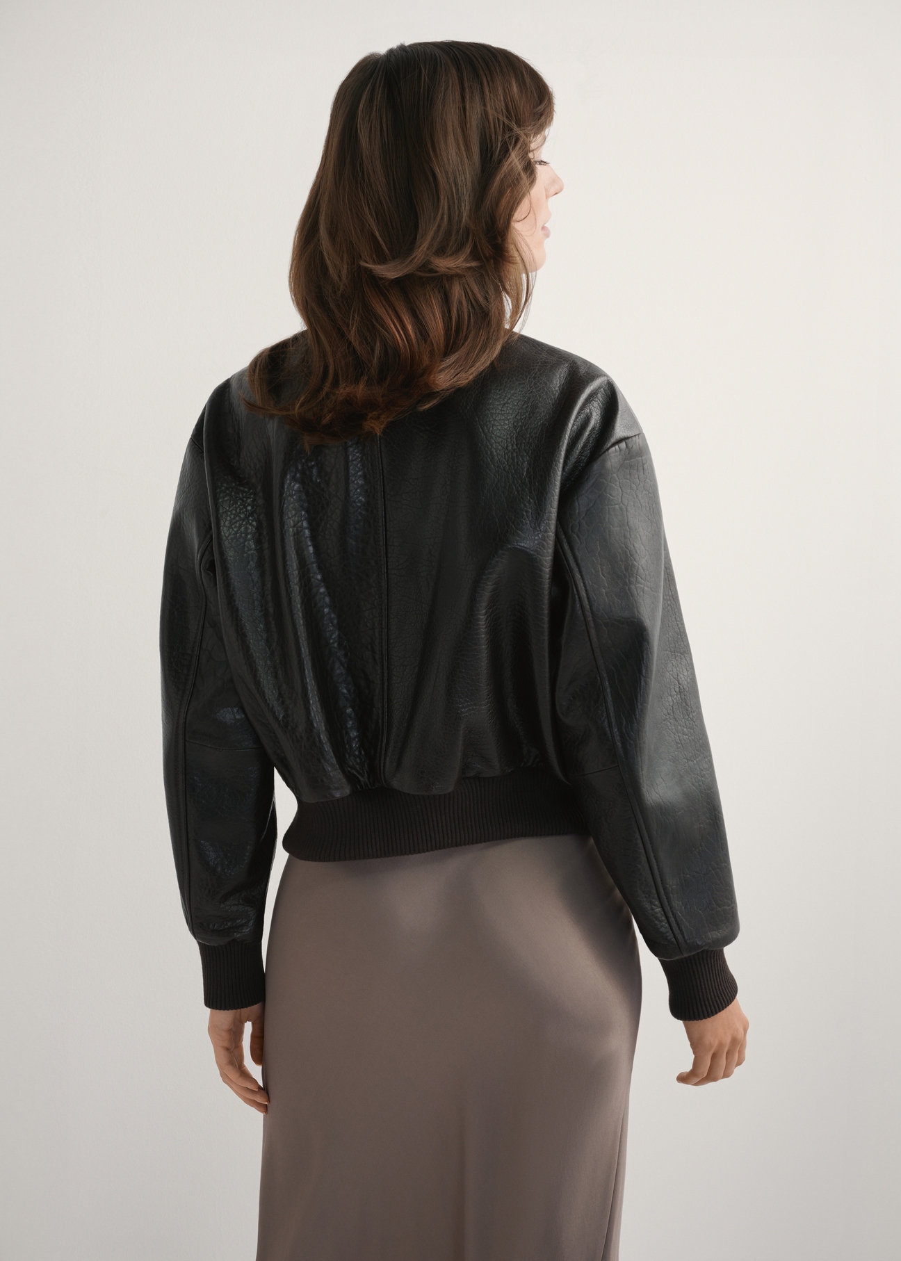 Women's brown leather jacket KURDS-0609-1I(W26), back view of the product on the model. Half of the silhouette visible.