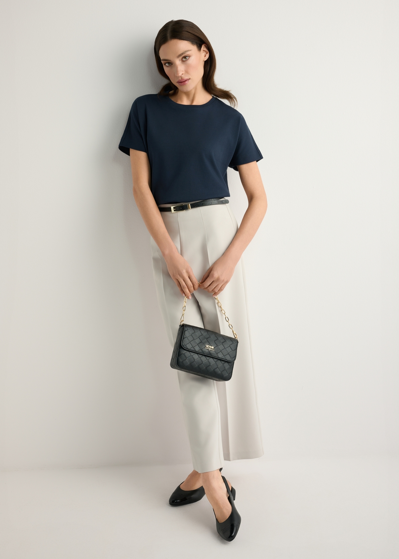 Black woven women's handbag TOREC-0767-9P(W26) - front view of the product, held by the model, against a light background. The entire silhouette is visible.