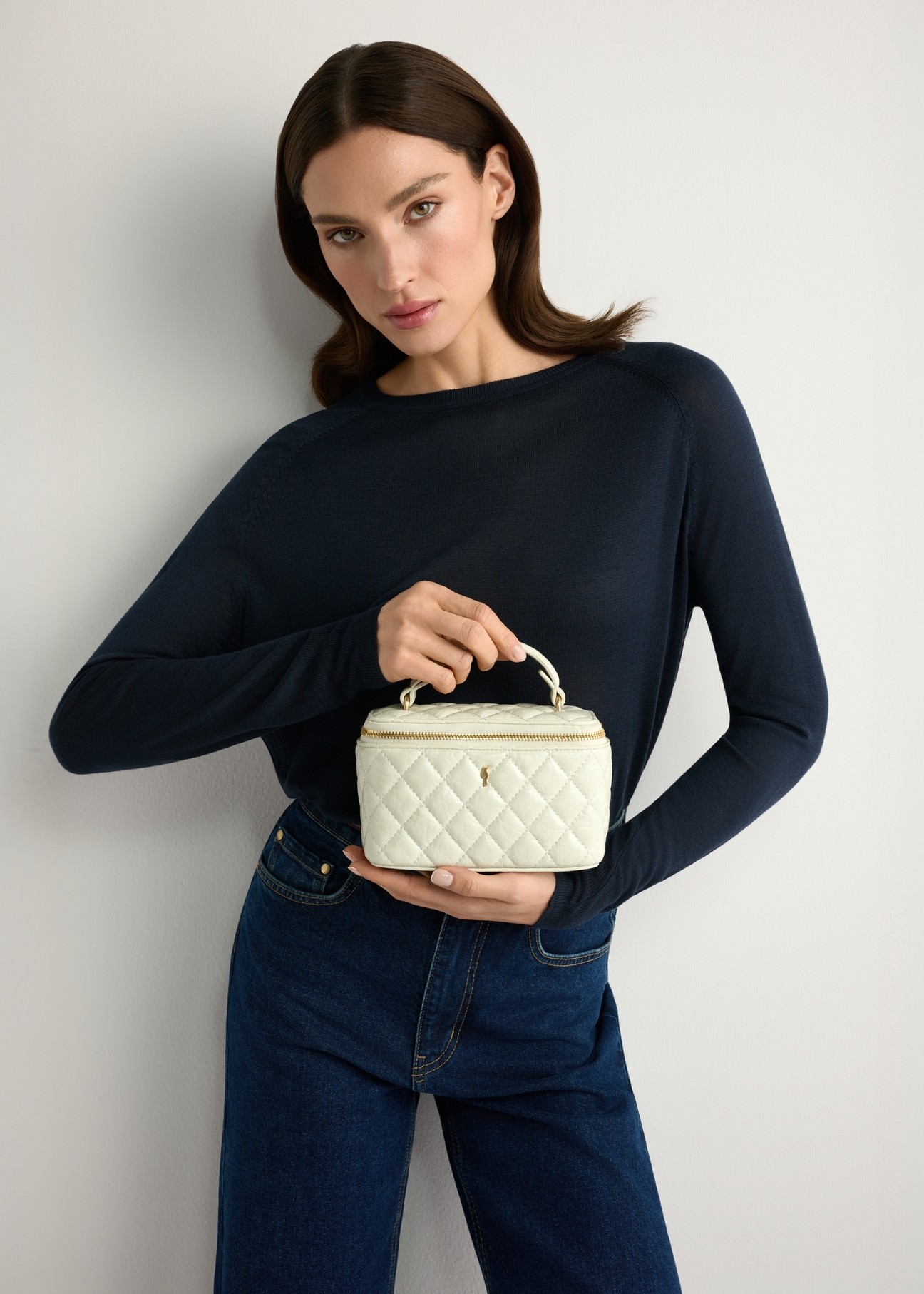 Cream women's cosmetic bag TOREC-1197-0A(W26) - front view of the product, held by the model, against a light background. Half-length silhouette visible.