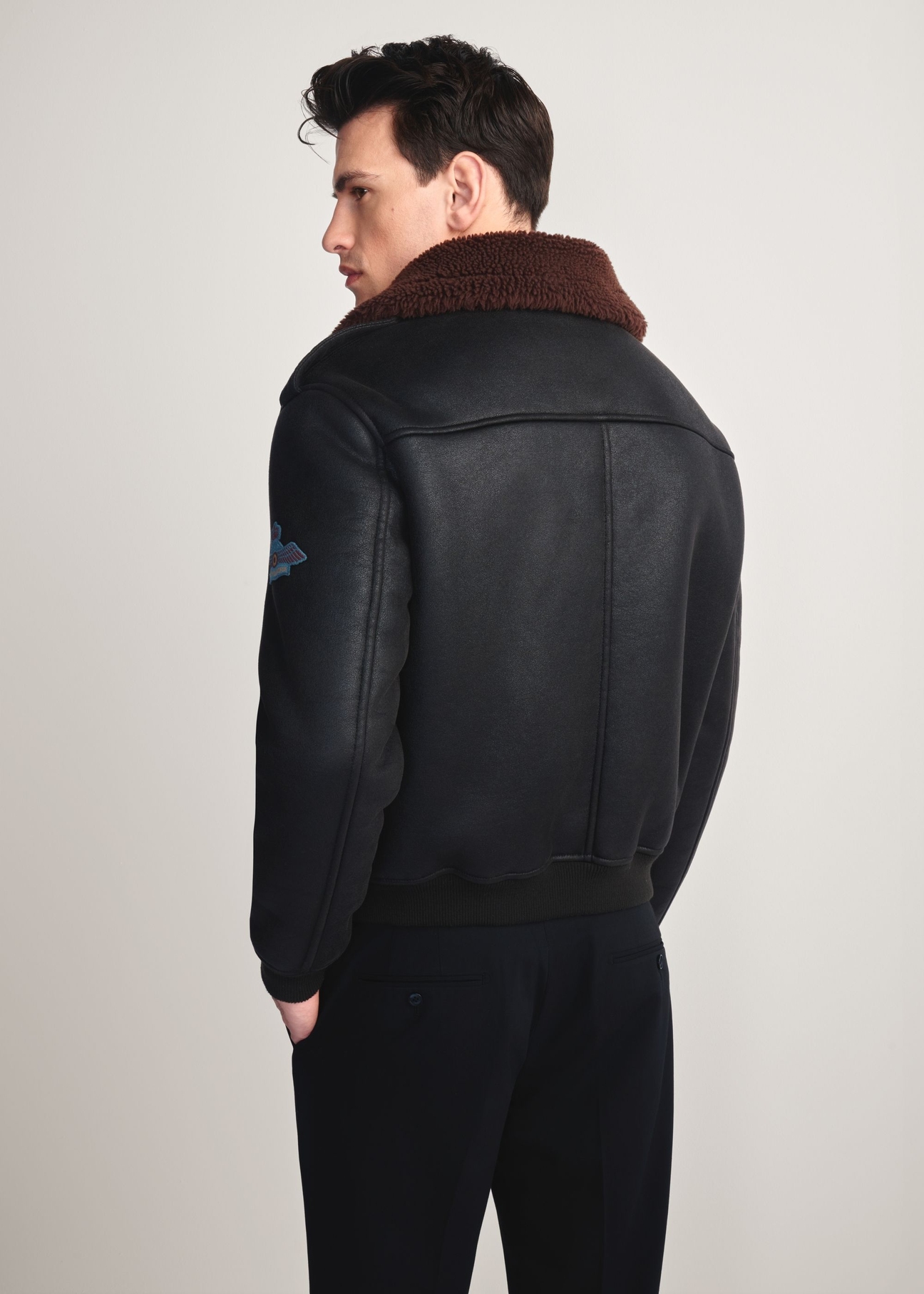 Men's brown aviator-style sheepskin coat KOZMP-0007-1I(Z26) - back view of the product modeled on a white background. Knee-length silhouette visible.
