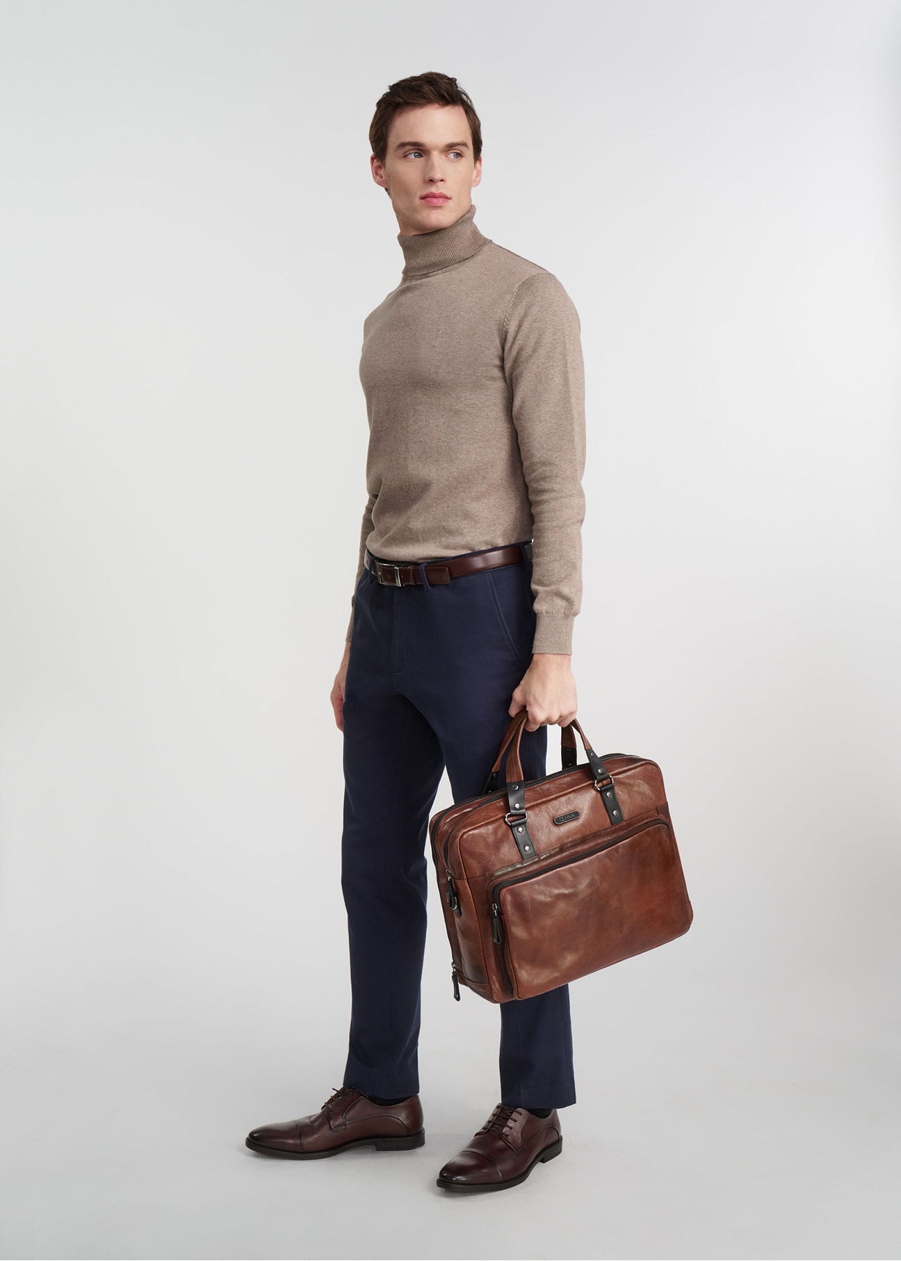 Brown leather men's bag TORMS-0100-1H(W26), product view in model's hand, against a light background. Full body visible.