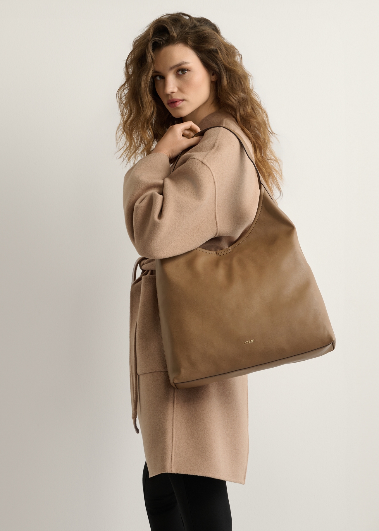 Large camel-colored women's handbag TOREC-1199-1D(W26), product view on model's shoulder. Half of silhouette visible.