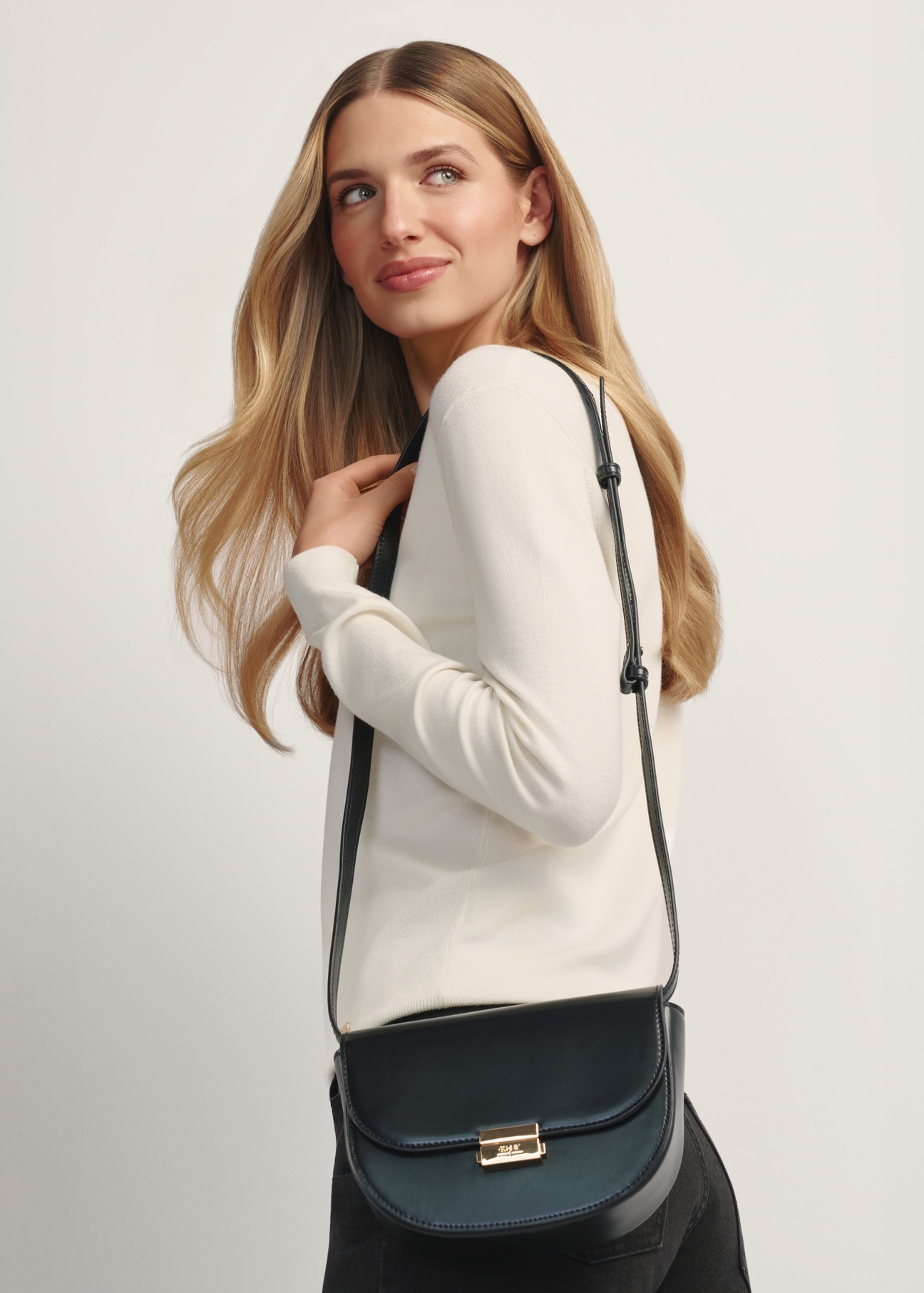 Black semi-circular women's messenger bag TOREC-1127-99(W26), front view of the product on a model, half of the silhouette visible.