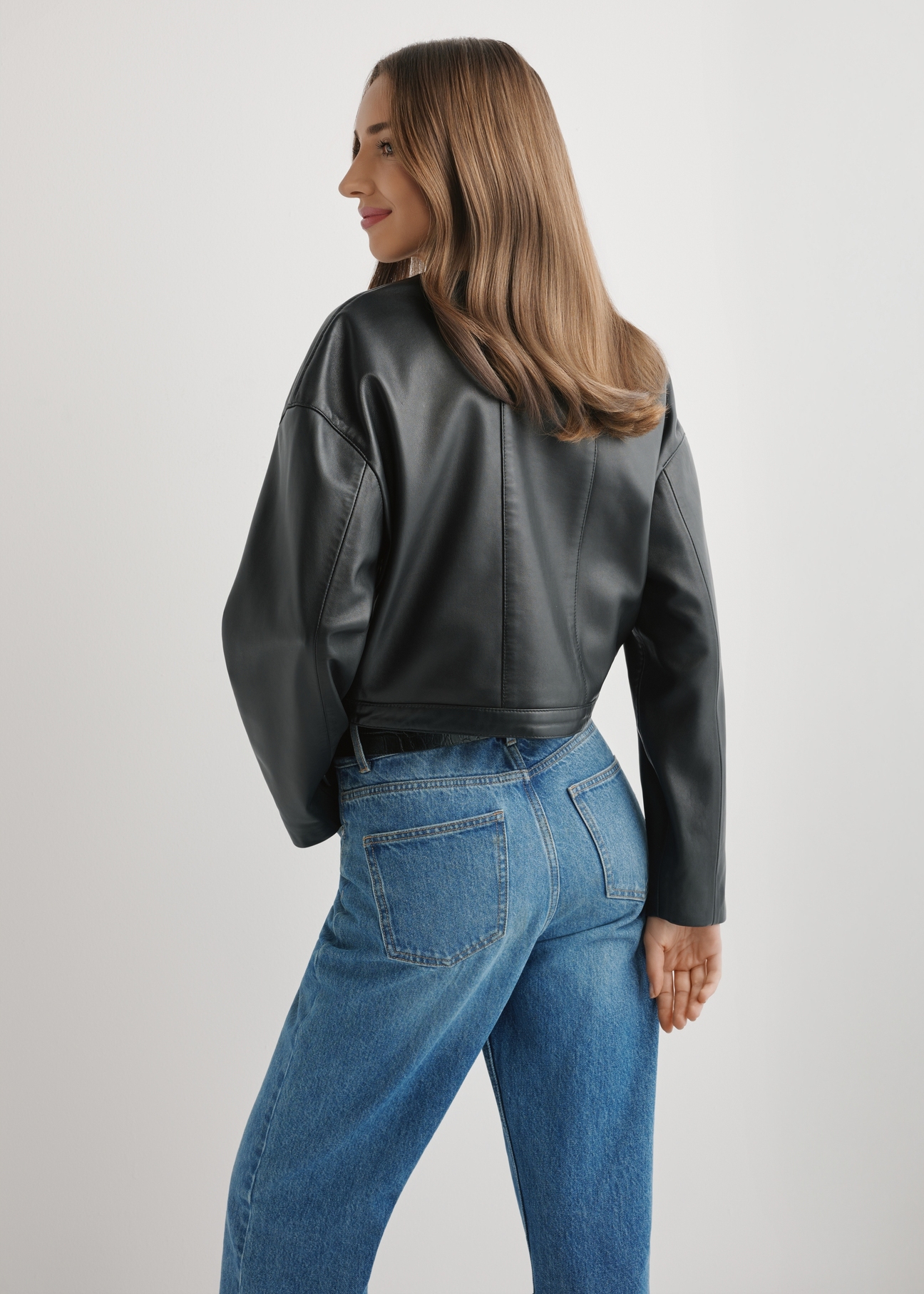 Women's short black leather jacket KURDS-0597-99(W26), back view of the product on the model. Half of the silhouette visible.