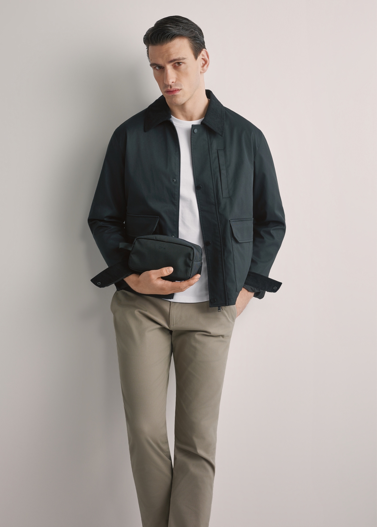 Black men's cosmetic bag TORMN-0352-99(W26), front view of the product in the model's hand. Half of the silhouette visible.