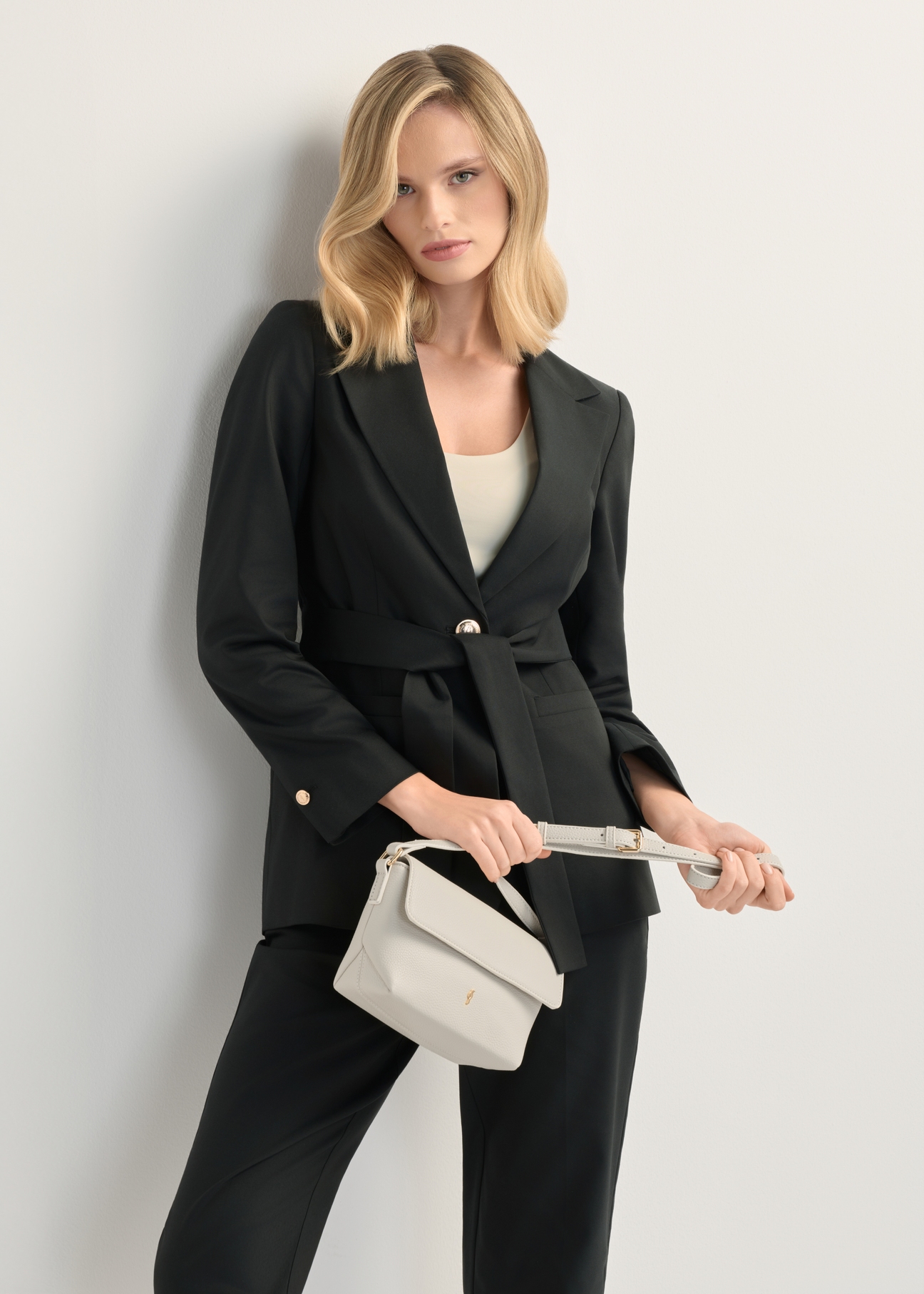 Cream small women's shoulder bag TOREC-0916-0B(W26), front view of the product in the model's hand. Half of the silhouette visible.