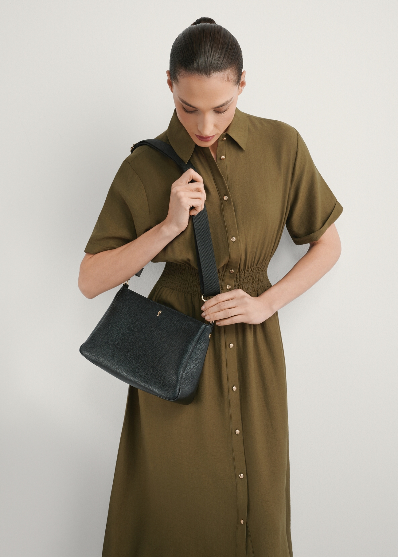 Women's black leather messenger bag TORES-1214-9I(W26), front view of the product on a model, half of the silhouette visible.