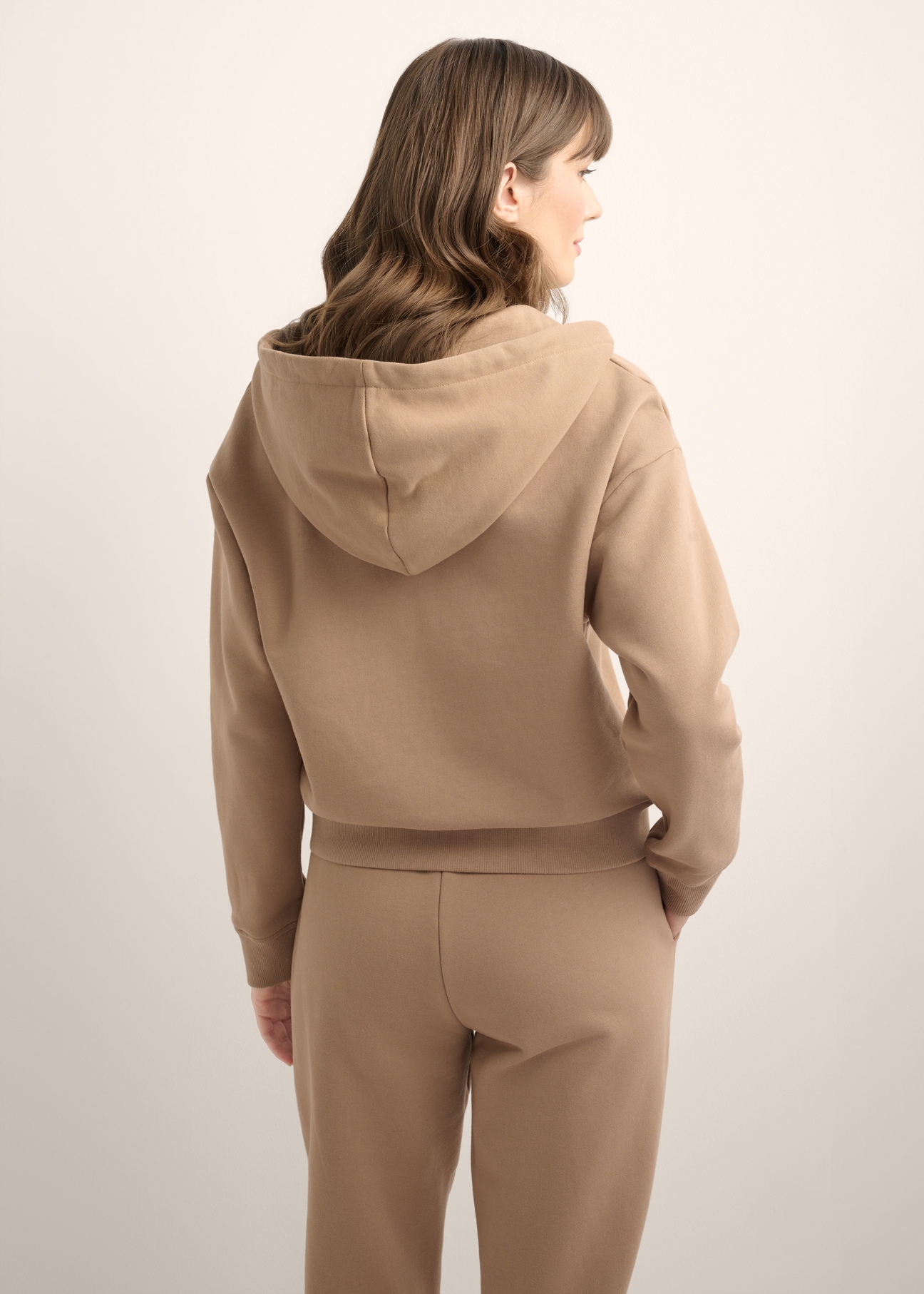 Women's camel zip-up hoodie BLZDT-0122-1D(Z26), product view from the back on the model. Half of the silhouette visible.