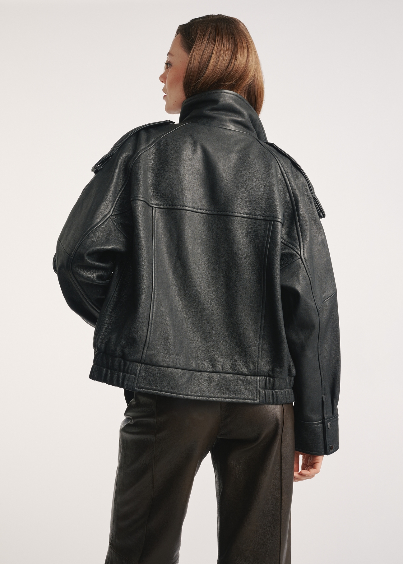 Women's black leather jacket KURDS-0554-2701(Z25) - back view of the product on a model, against a white background. Knee-length silhouette visible.