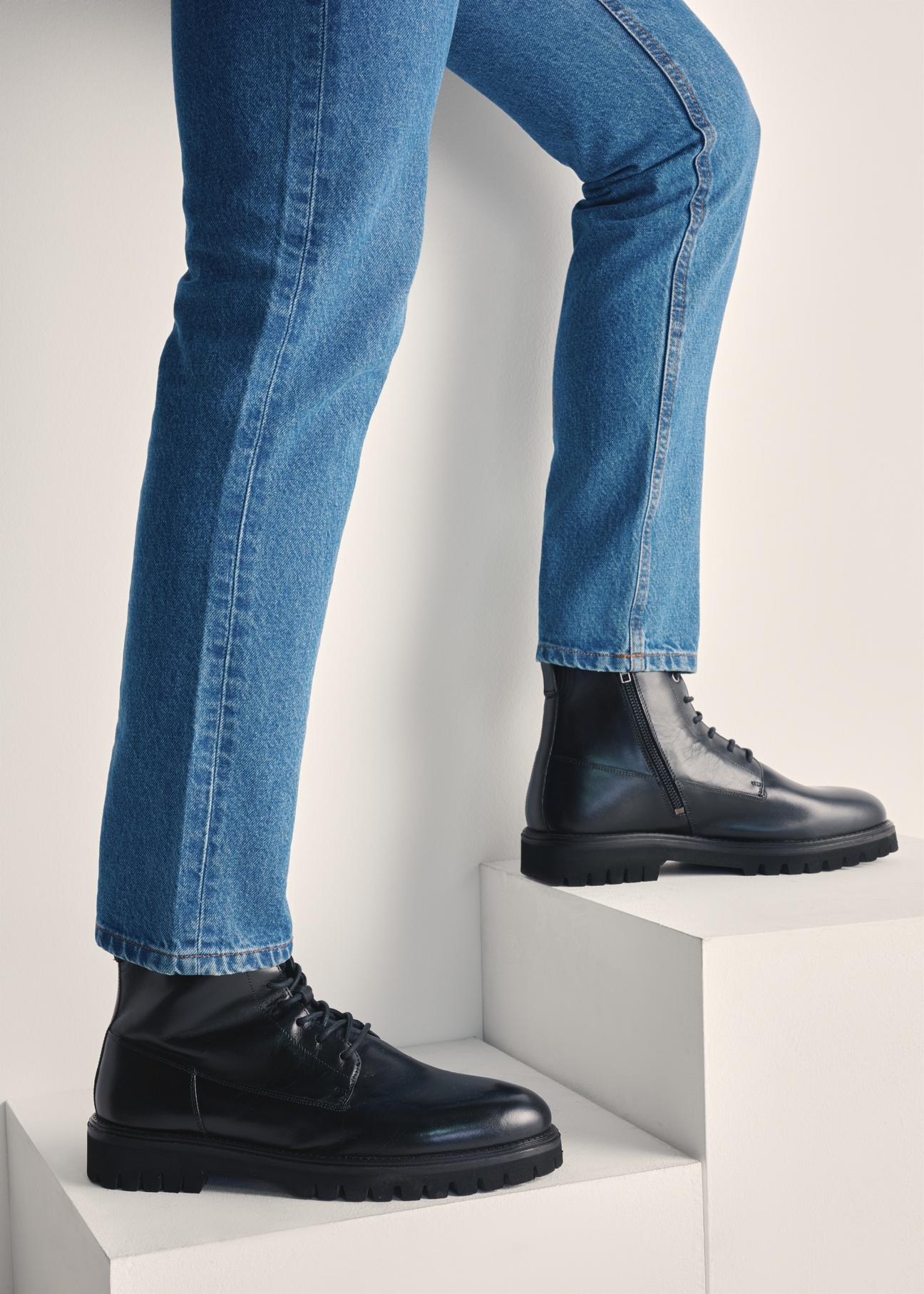 Men's black leather ankle boots BUTYM-0507-99(Z25), side view of the product on the model's feet against a light background.