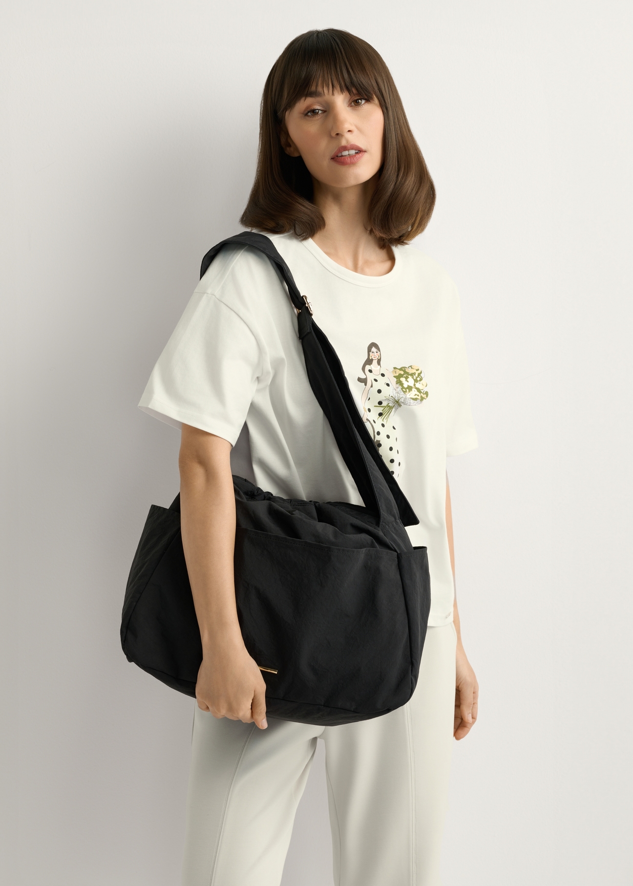 Black nylon bucket bag TOREN-0337-99(W26), product view on model's shoulder. Half of silhouette visible.