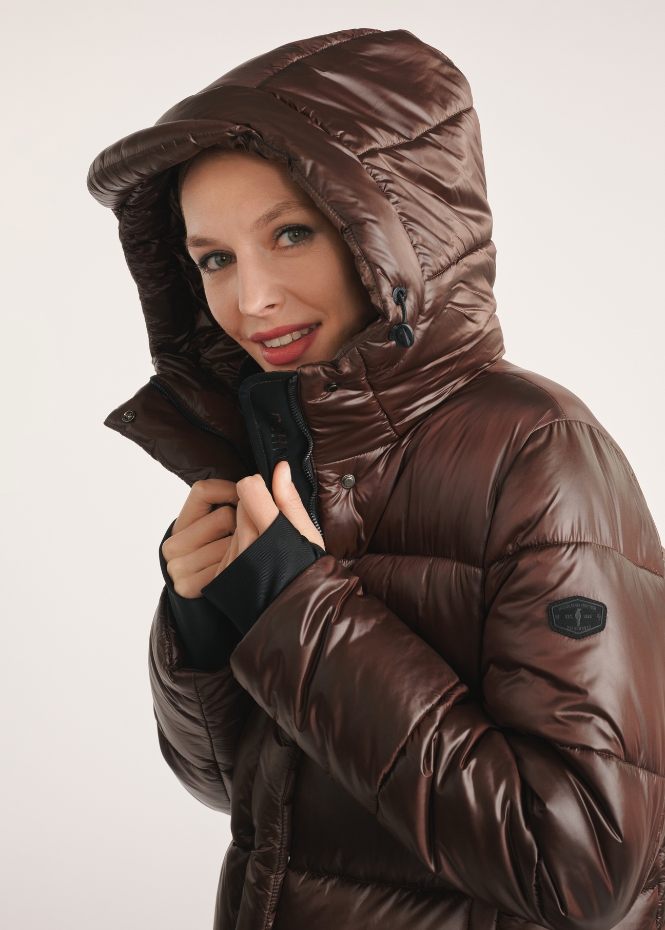 Brown long women's winter jacket KURDT-0531-89(Z25) - close-up of detail on model on white background. Half of the silhouette visible.