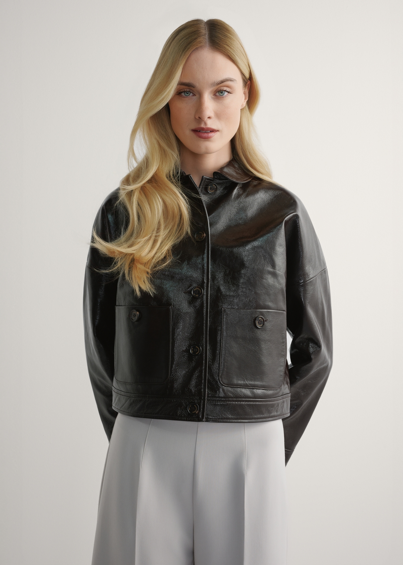 Women's brown short leather jacket KURDS-0593-1I(W26) - front view of the product, on a model, against a light background. Knee-length silhouette visible.