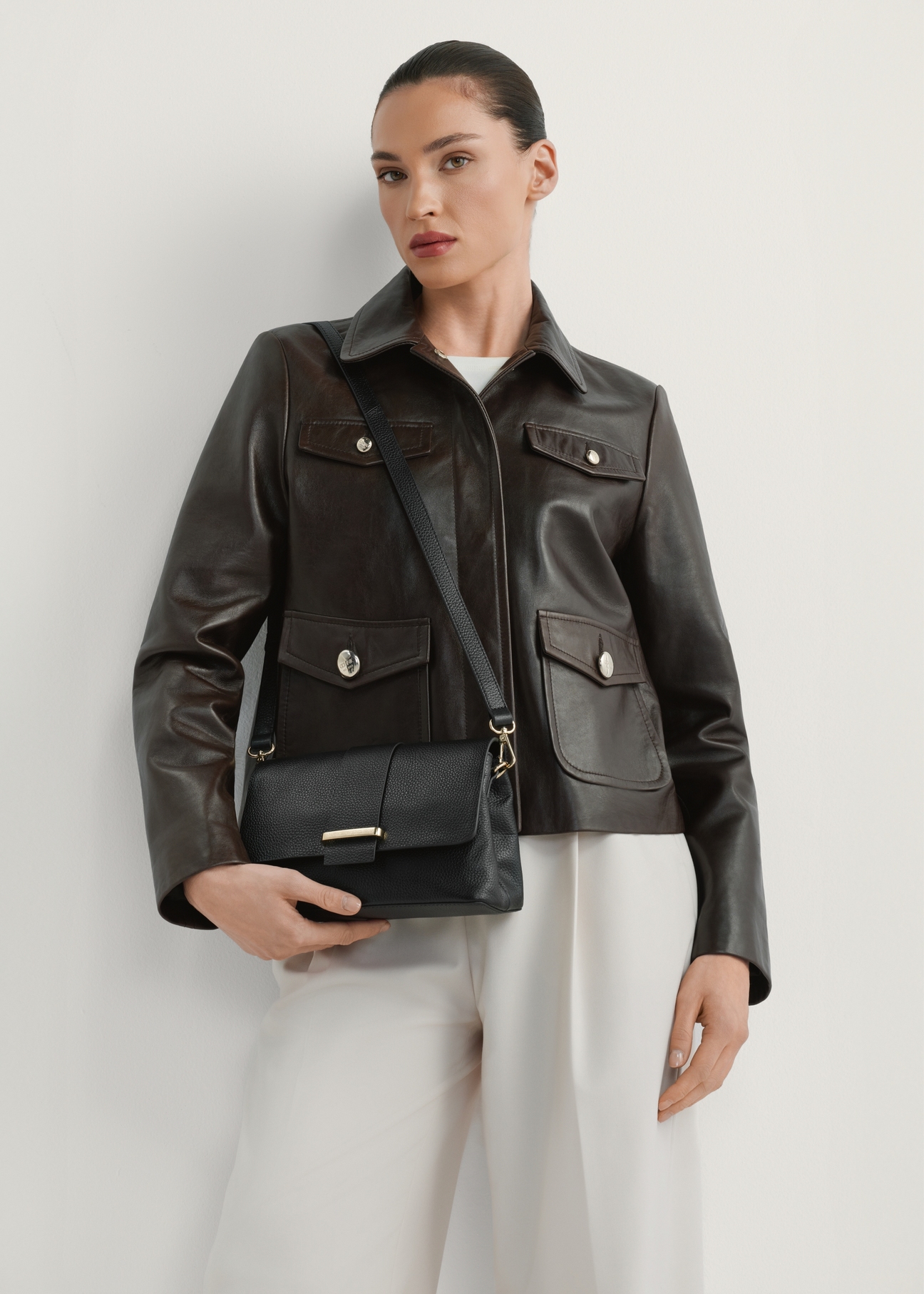 Women's black leather handbag TORES-1220-9I(W26) - front view of the handbag, on a model, against a light background. Knee-length silhouette visible.