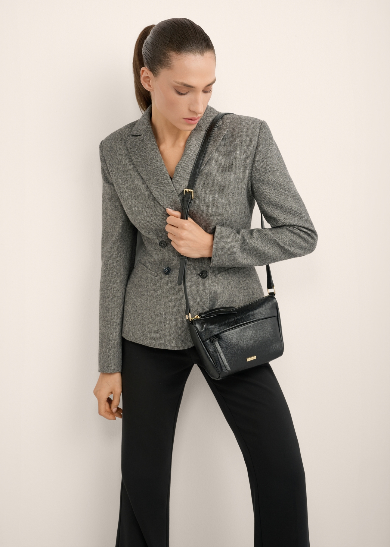 Small black women's imitation leather handbag TOREC-1367-9I(Z26), product view on model's shoulder. Half of silhouette visible.
