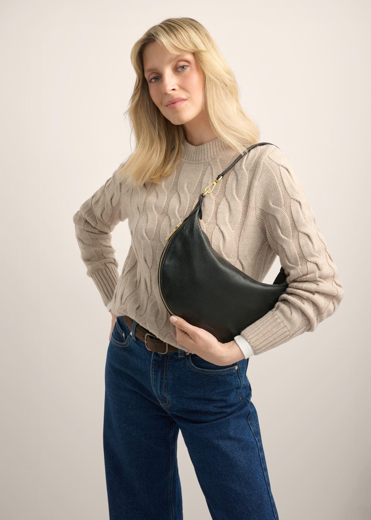 Black leather semi-circular women's handbag TORES-1336-9I(Z26), front view of the product on a model. Half of the silhouette visible.