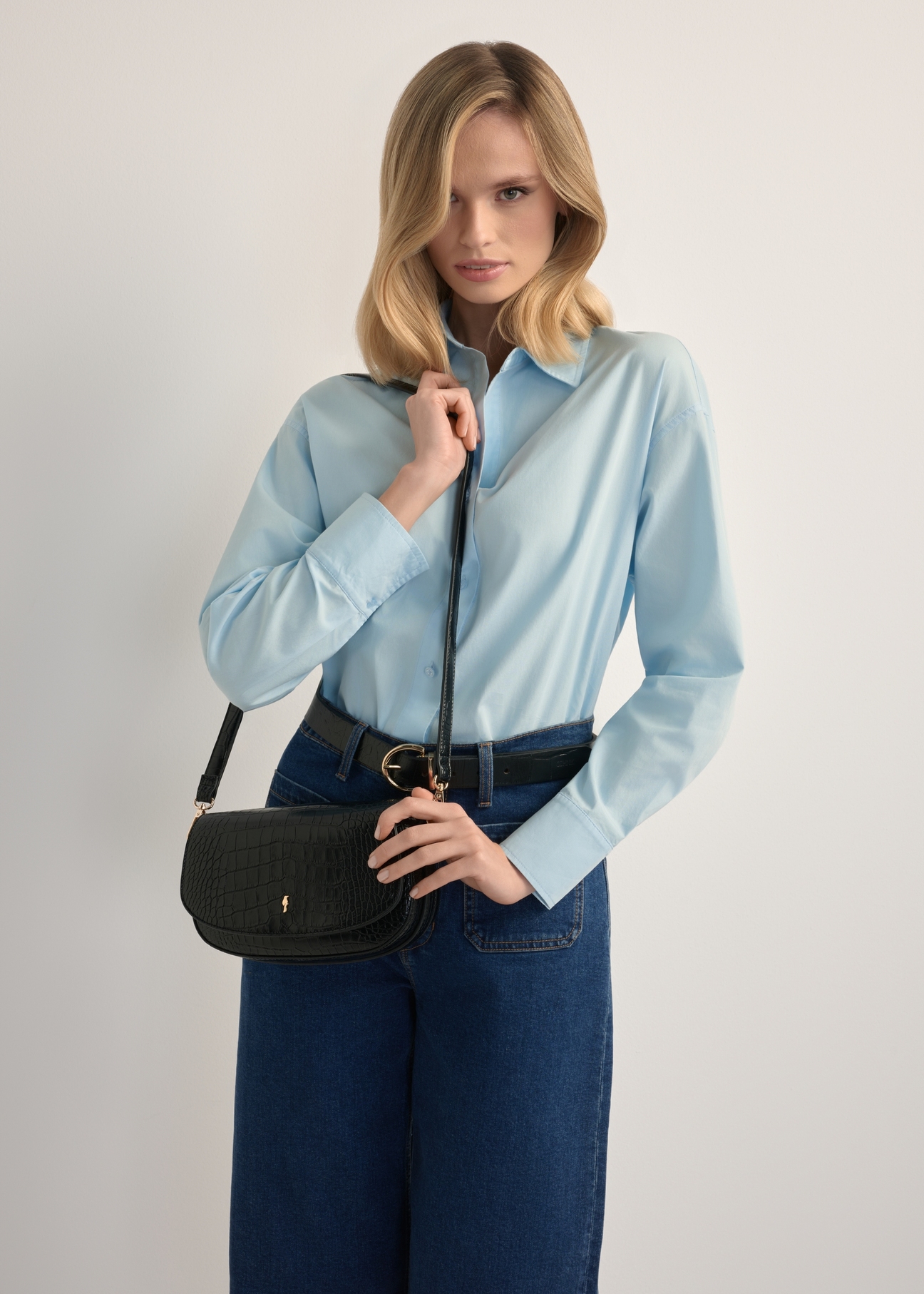 Small black women's croco messenger bag TOREC-1185-9G(W26), product view on model's shoulder. Half silhouette visible.