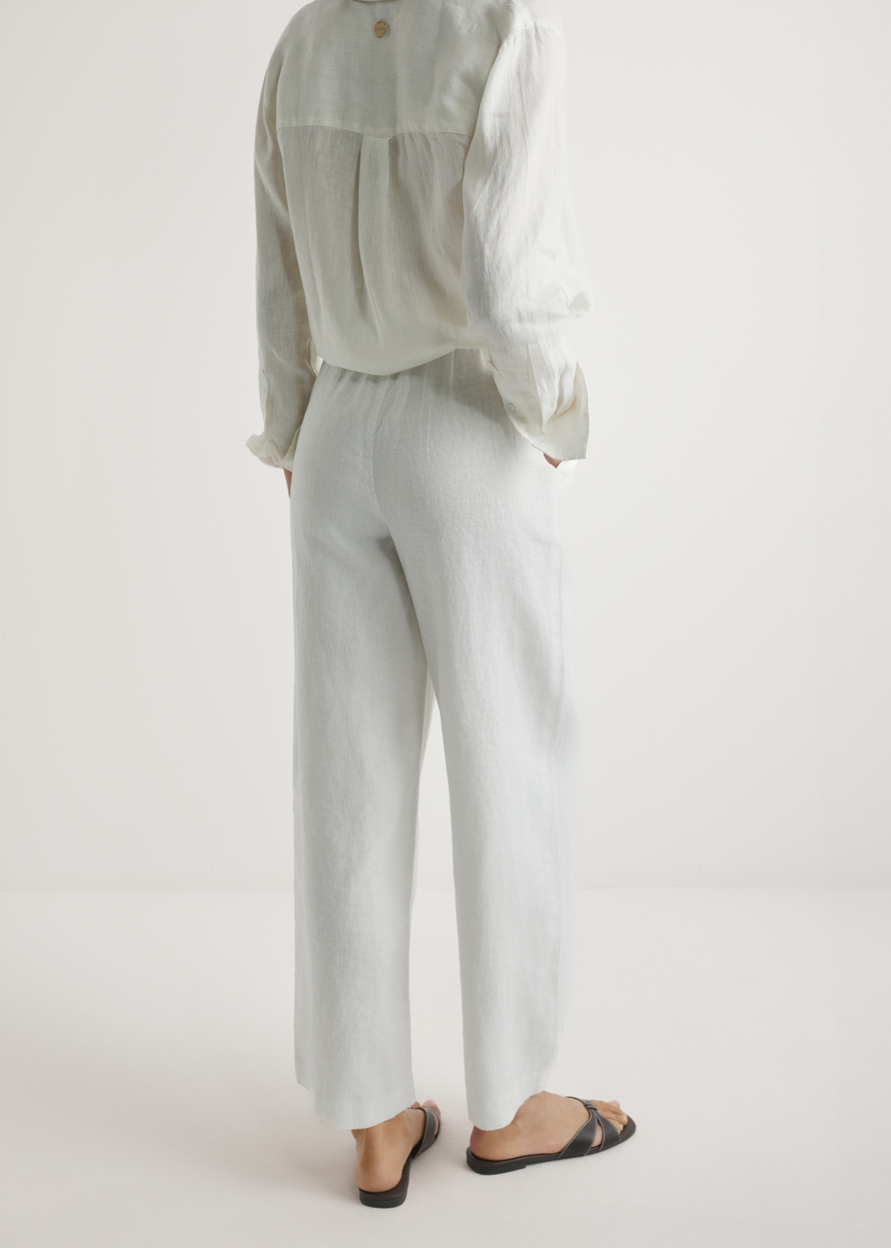 Light beige linen women's trousers SPODT-0124-1A(W26), product view from the back on the model, half of the silhouette visible.
